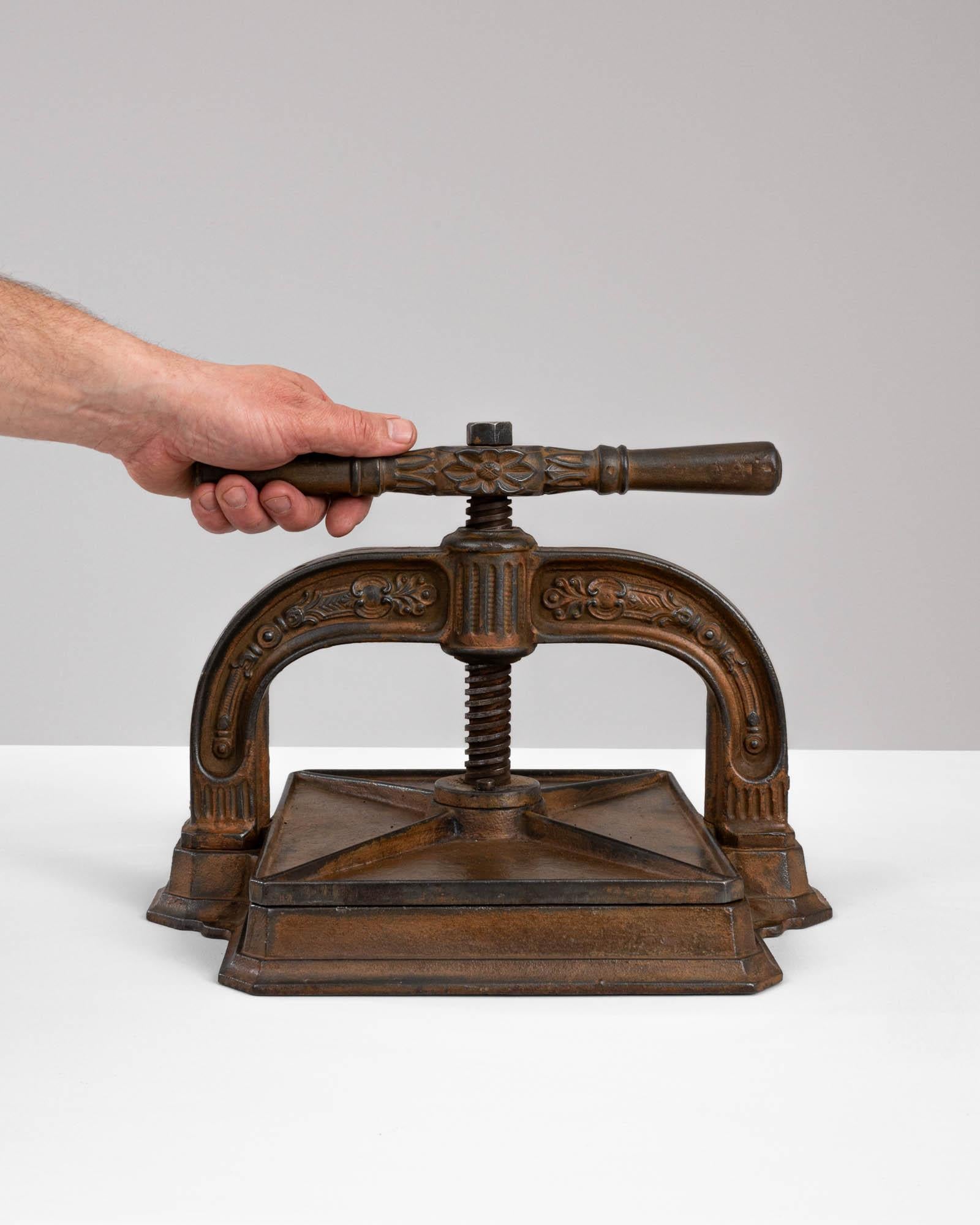A cast iron press from 20th Century Belgium. Originally purposed as a book-binding press used in such places as banks or libraries, this unique antiquity suggests a niche function, while providing a universal visual appeal. Its cast iron form,