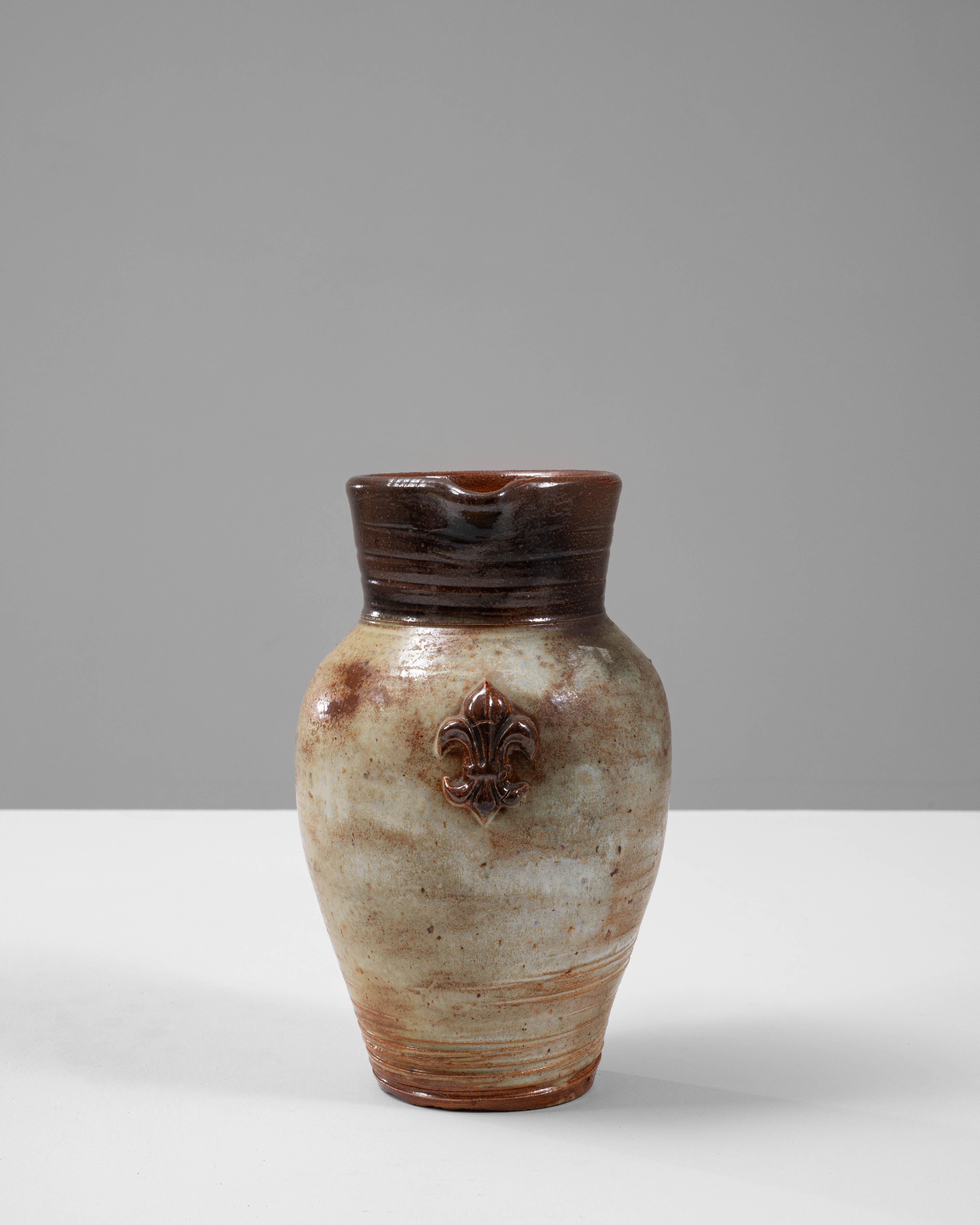 Cet exquis pichet en céramique belge du 20e siècle de G. Losson capture la beauté rustique de la poterie européenne. Le corps arrondi est recouvert d'une glaçure doucement mouchetée dans des tons de crème et de brun, créant un mélange harmonieux de