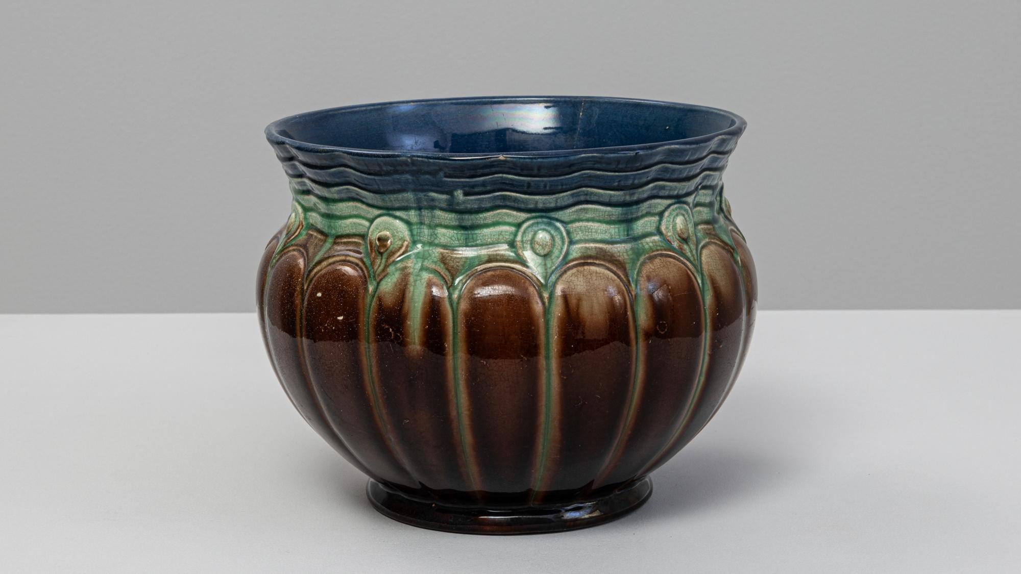 Jarrón de cerámica belga del siglo XX. Esta hermosa vasija esmaltada presenta una forma redondeada y lobulada con un escultural dibujo en relieve que rodea el cuerpo. El rico esmalte degradado pasa del marrón chocolate intenso en la base a vibrantes