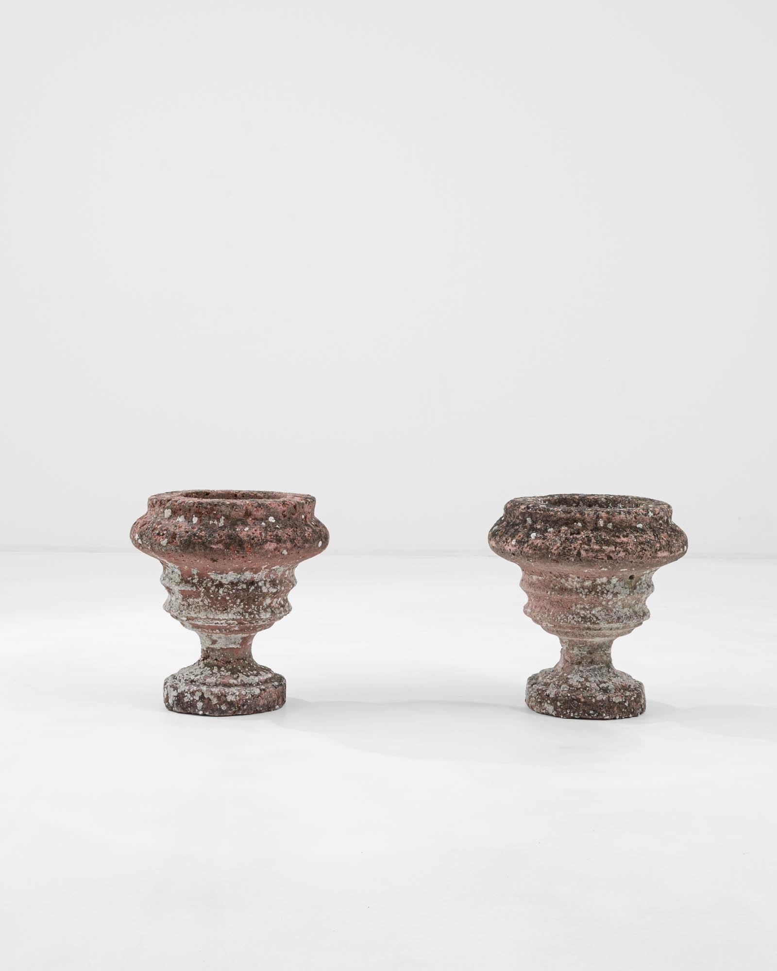 Weathered, pockmarked, and brimming with unique character, this pair of antique planters, created in 20th century Belgium, impart a timeless and delightful energy. A subtly organic, yet artfully shaped and tapering construction creates an