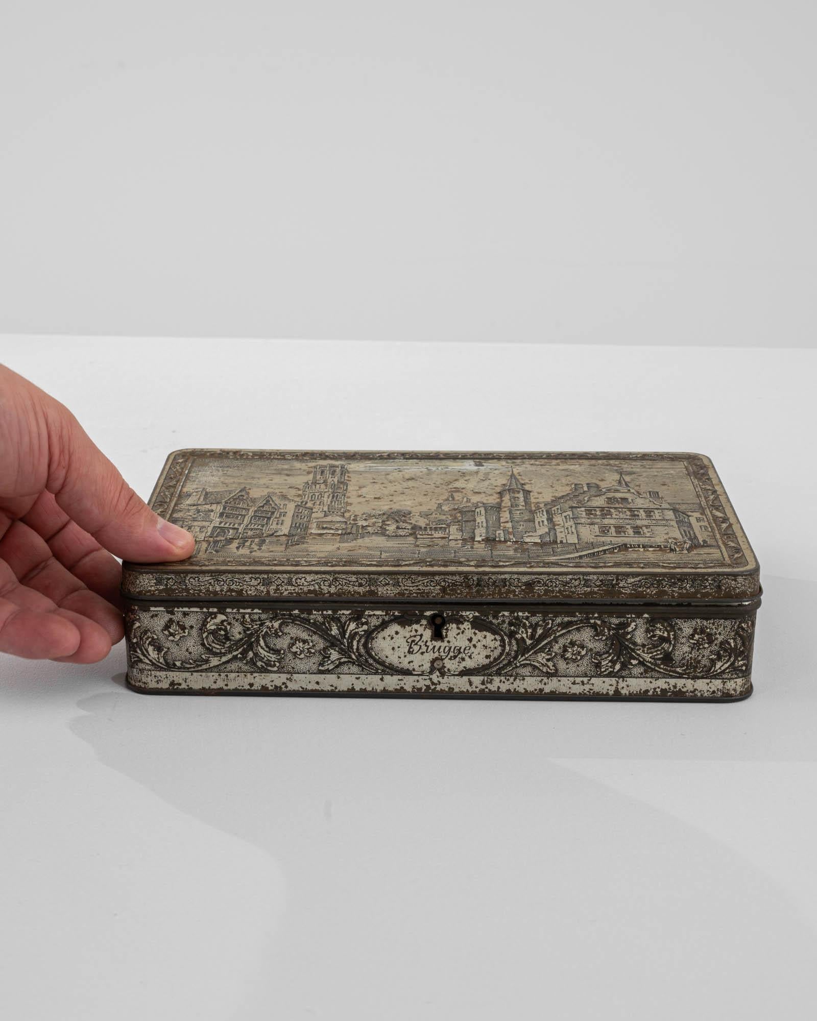 Embrace the charm of bygone eras with this 20th-century Belgian metal box, an evocative piece that captures the essence of Bruges. Adorning the top, a picturesque landscape unfolds, revealing the city's architectural marvels and streets in exquisite