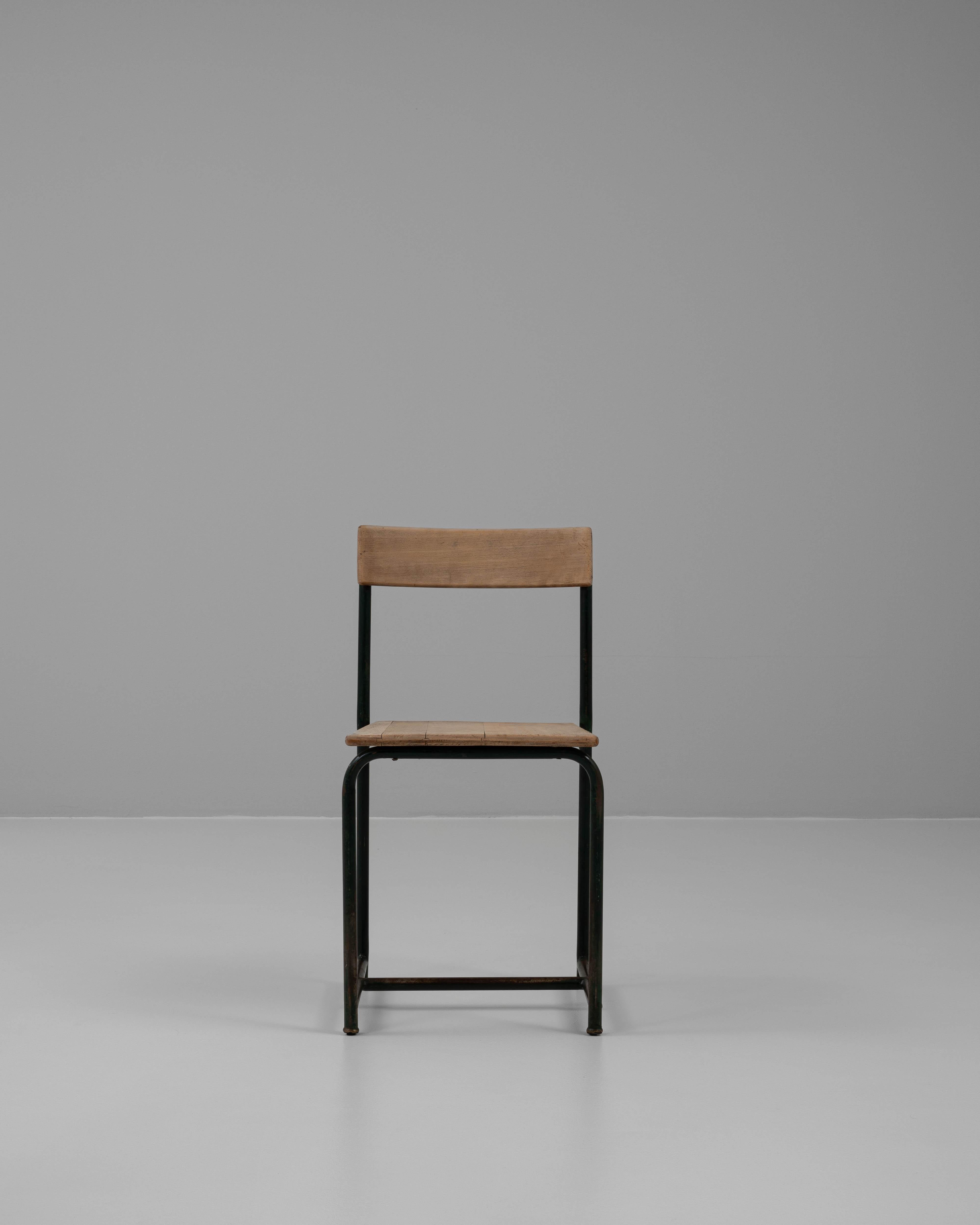 This 20th-century Belgian metal chair combines industrial design with timeless simplicity. Featuring a sturdy metal frame, the chair is accented by a natural wooden seat and backrest, which add warmth and character to its minimalist structure. The
