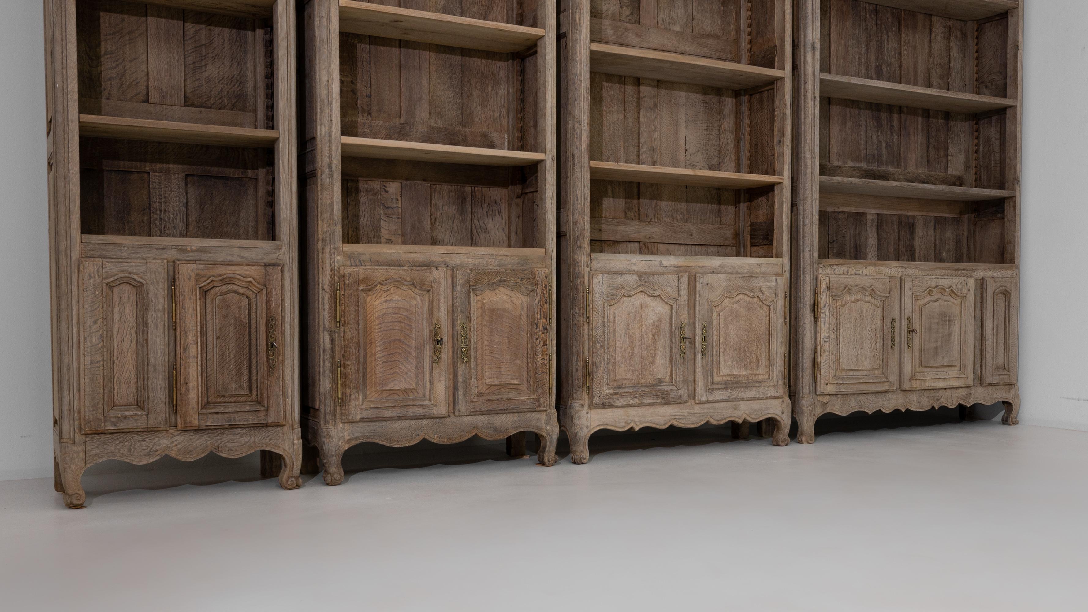 This set of four oak cabinets provides an accommodating storage solution with a vintage elegance. Built in Belgium in the 20th Century, paneled cupboards and scrolled cabriole feet form an elegant base from which rises a simple sequence of shelves.