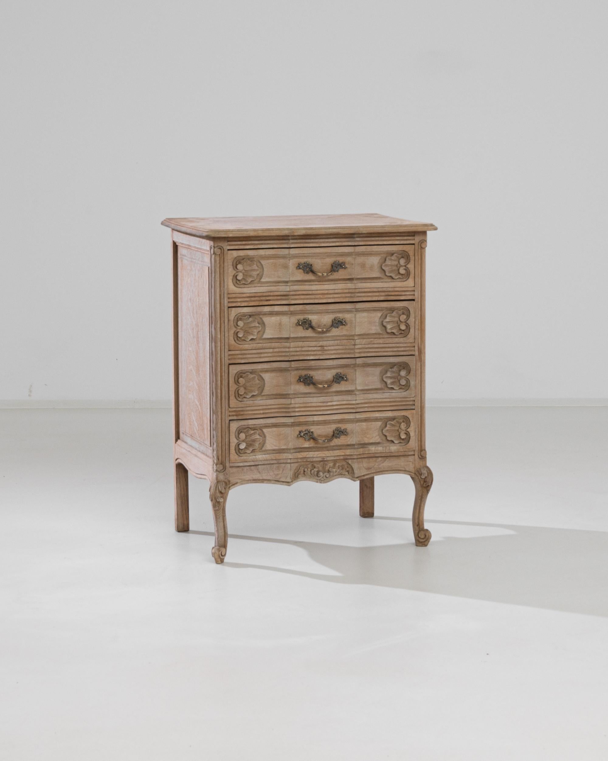 A vintage four-drawer chest from Belgium. Raised on slender cabriole legs, this 20th century dresser boasts classical ornamental seashell and plant motifs, carved on the drawers, apron and front feet. The foliate theme is continued on the gilded