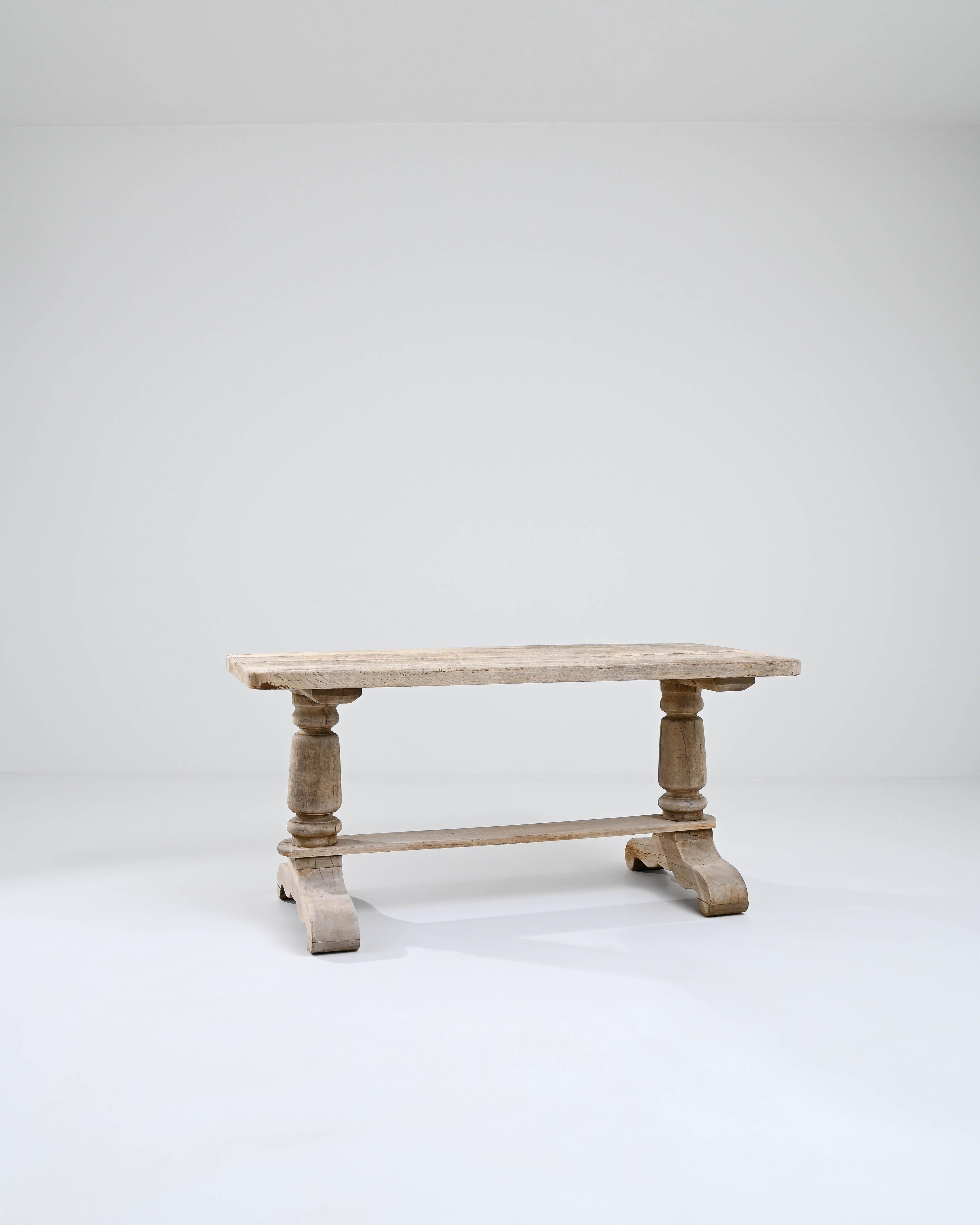 Both sturdy and graceful, this oak dining table cuts an eye-catching figure. Made in Belgium in the 20th century, the form reflects the traditional Provincial styles of the Flemish countryside. A simple rectangular table top rests atop a trestle