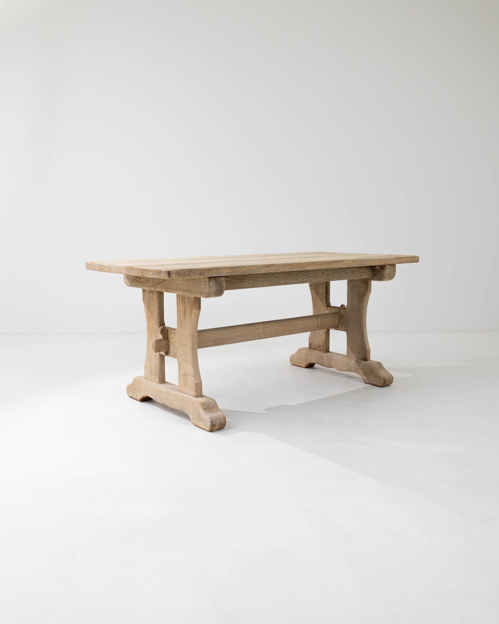 This vintage oak dining table offers a traditional design, beautifully crafted. Hand-built in Belgium in the 20th century, the rectangular tabletop sits atop a trestle base. The simple country silhouette is subtly embellished by the softly carved