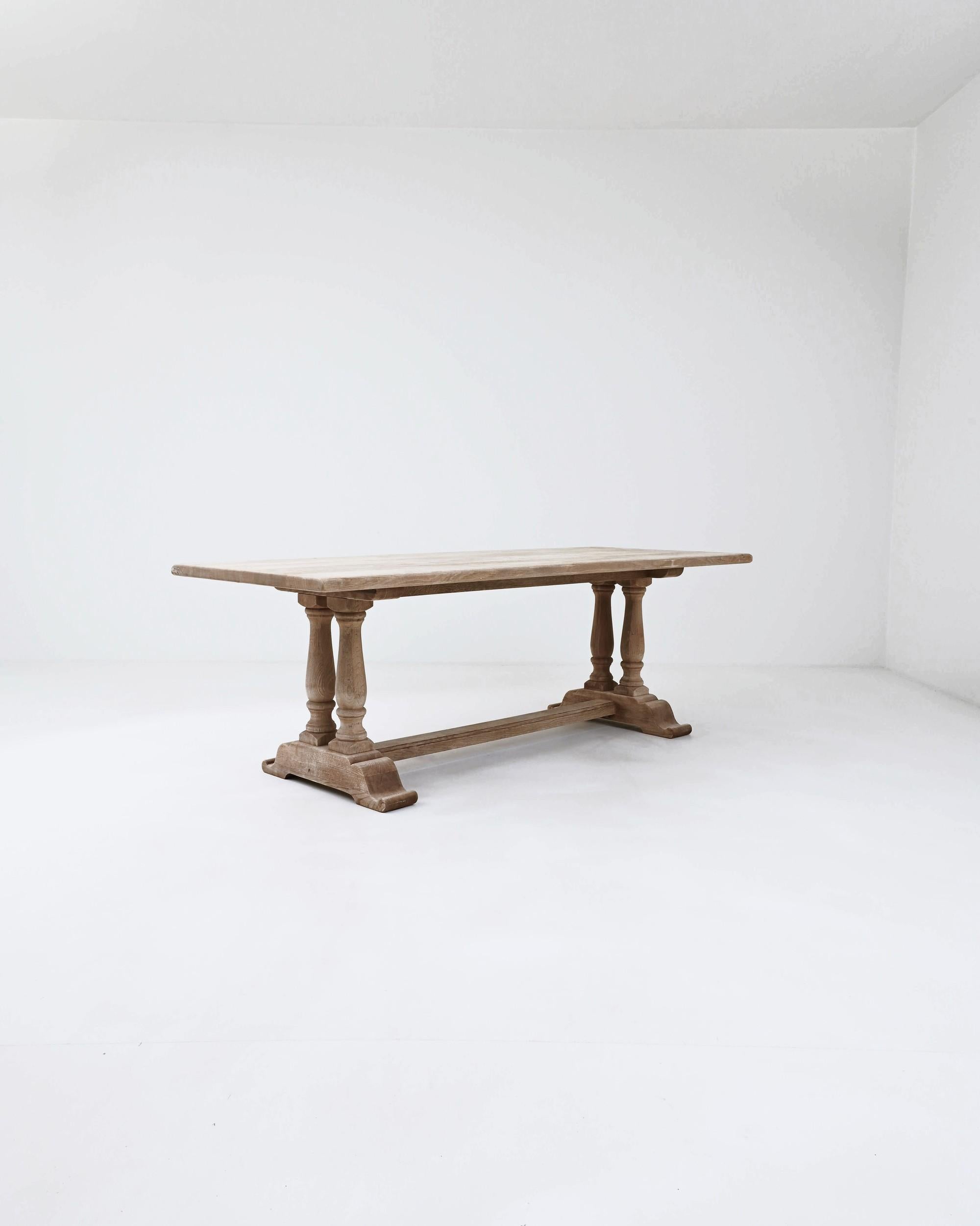 This vintage oak dining table offers a beautiful Provincial centerpiece. Hand-built in Belgium in the 20th century, a simple rectangular tabletop sits atop a trestle base. The columns of the turned legs create an attractive profile, while the wide