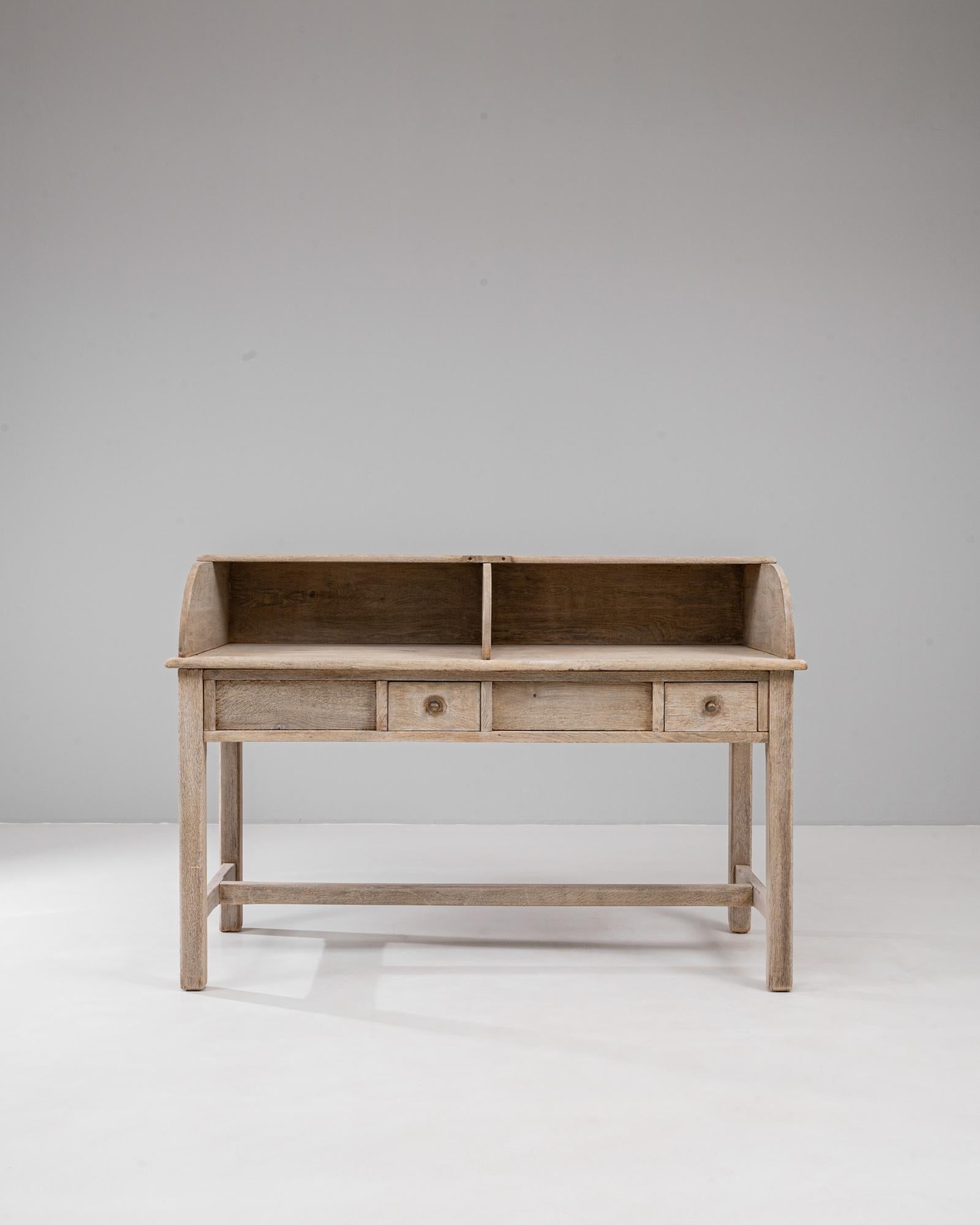 Scrivania in Oak belga del XX secolo con cassetti. Realizzata in rovere massiccio con una patina splendidamente schiarita, questa scrivania belga incarna sia la funzione che il fascino. Il suo caratteristico piano superiore presenta dei divisori