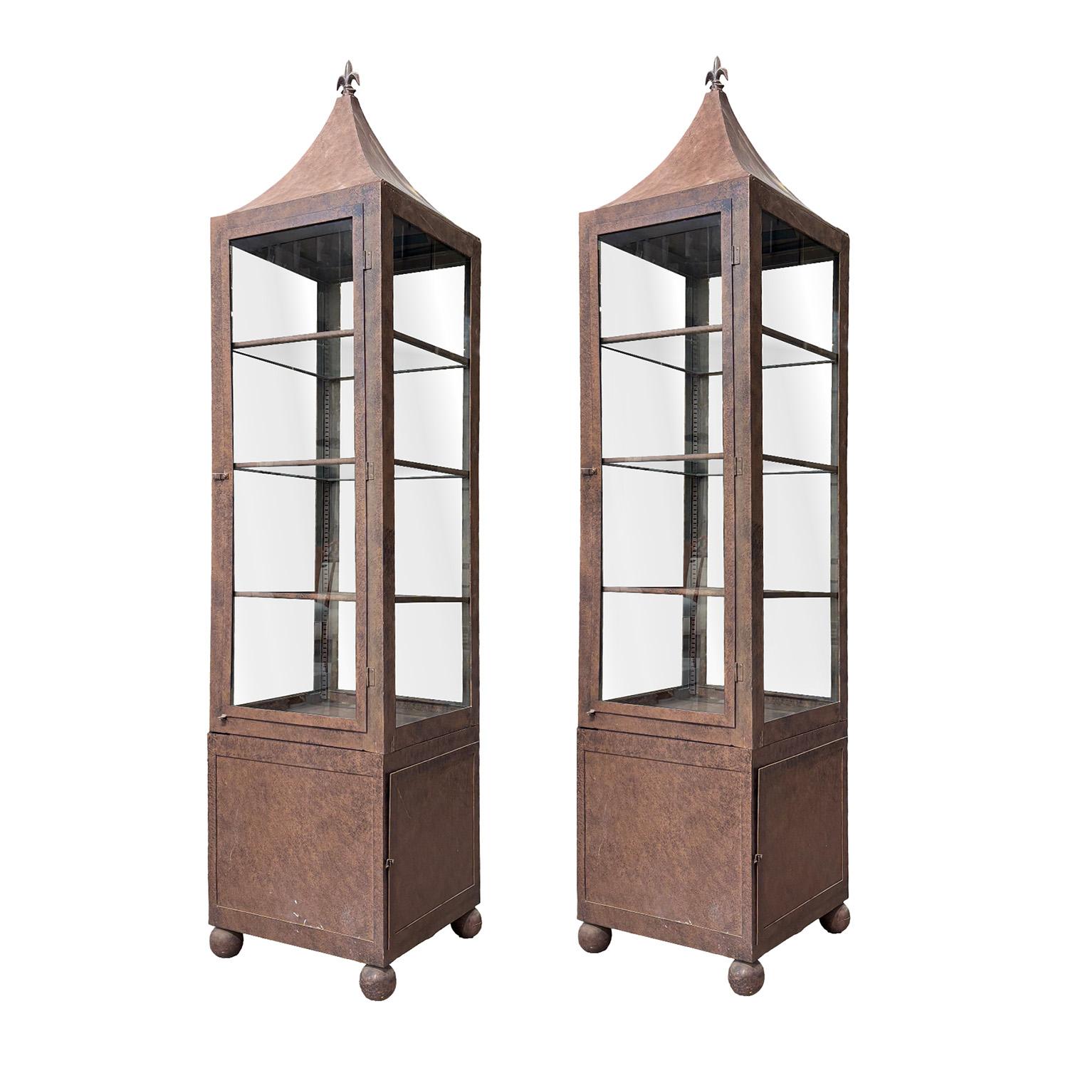 A tall, vintage pair of Mid-Century modern Belgian two-part vitrines made hand crafted metal, in good condition. Each of the detailed Industrial style glass display cabinets are composed with three shelfs, the base is consisting a door and a light,