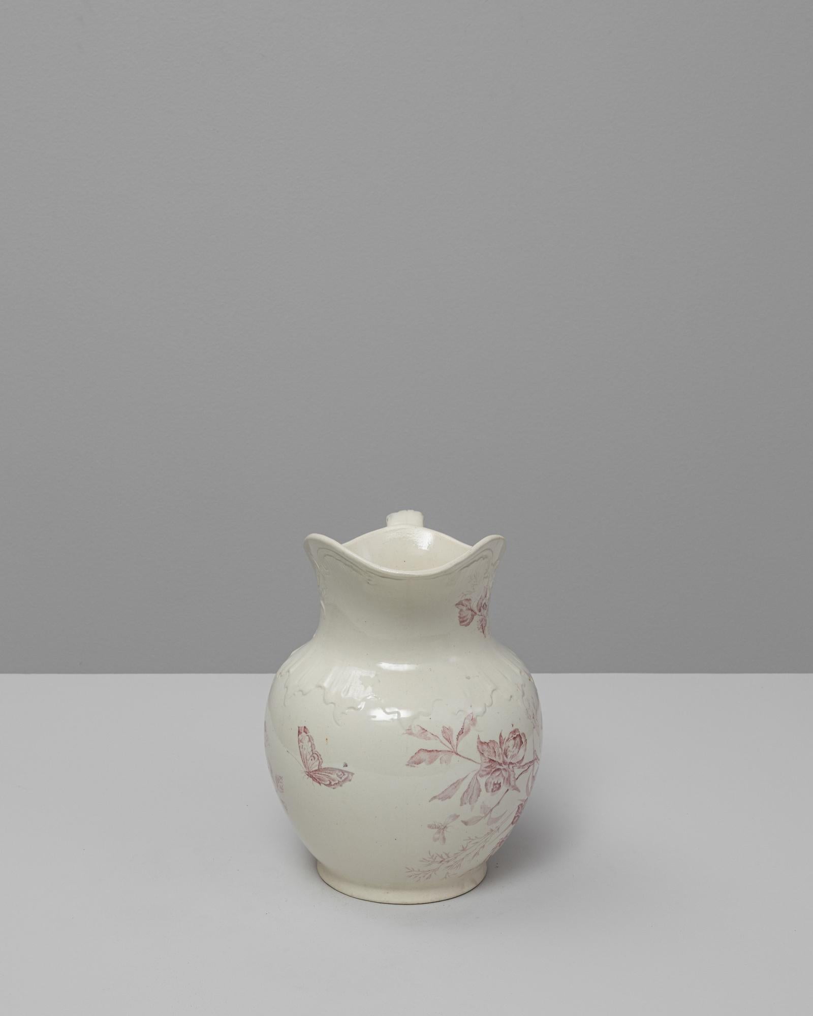 Ce pichet en céramique rouge Chinoiserie belge du 20e siècle combine une forme européenne élégante avec de délicats motifs inspirés de l'Asie de l'Est. Le corps généreusement arrondi, le col festonné et la poignée gracieusement incurvée créent une