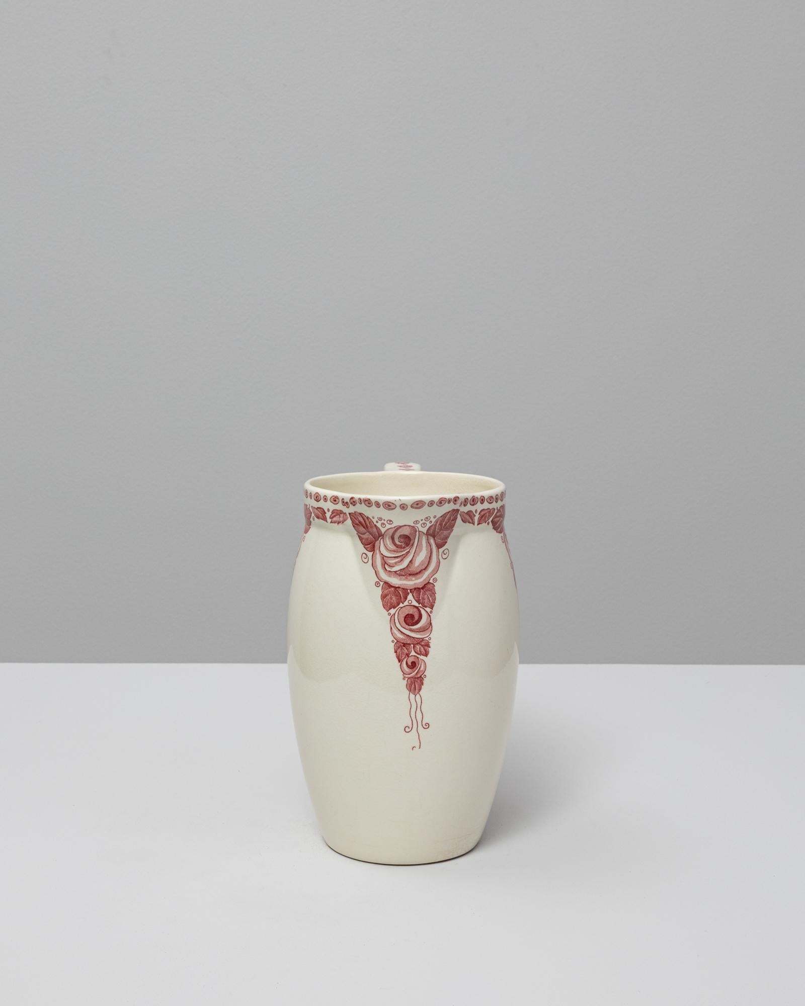 Ce pichet en céramique rouge Chinoiserie belge du 20e siècle présente une silhouette gracieuse et effilée complétée par de délicats ornements d'inspiration orientale. La glaçure crémeuse constitue une toile de fond douce et neutre pour les motifs