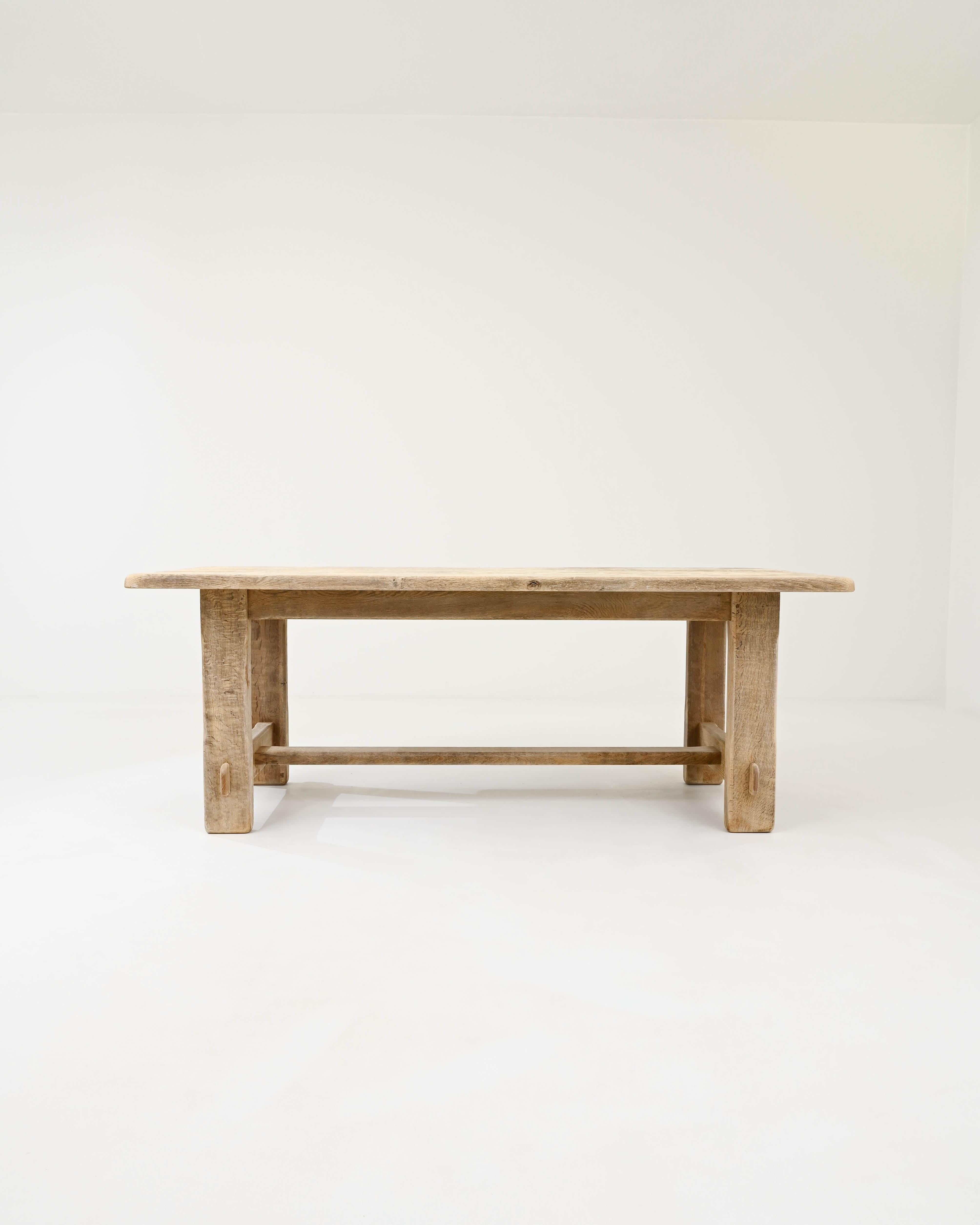 The rustic form and organic finish of this vintage oak dining table makes it an attractive centerpiece. Built in Belgium in the 20th century, the design offers a playful interpretation of the typical Provincial trestle table, making use of flat