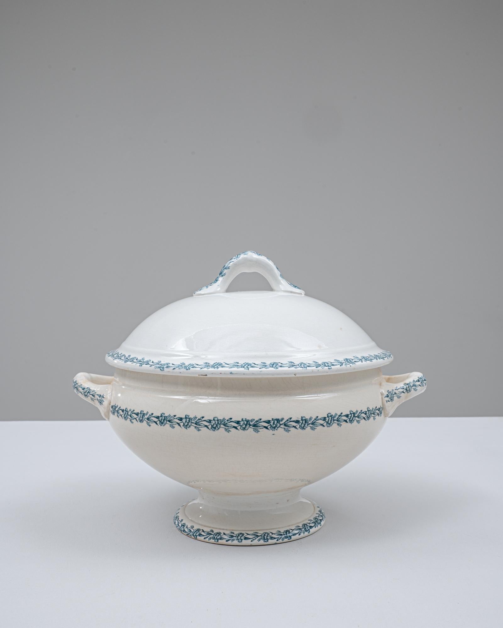 Cette soupière en porcelaine belge du 20e siècle, édition spéciale, présente une silhouette arrondie classique élevée sur un socle évasé, offrant à la fois élégance et prestance. Le couvercle bombé est surmonté d'une poignée en boucle sculptée,