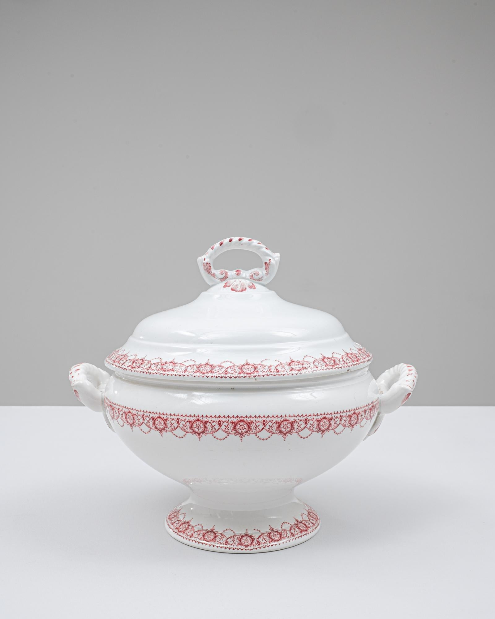 Cette soupière en porcelaine belge du 20e siècle, édition spéciale, présente une forme raffinée sur pied enrichie d'un motif de transfert rouge complexe qui entoure le couvercle, le corps et la base. L'émail blanc vif offre une toile de fond nette