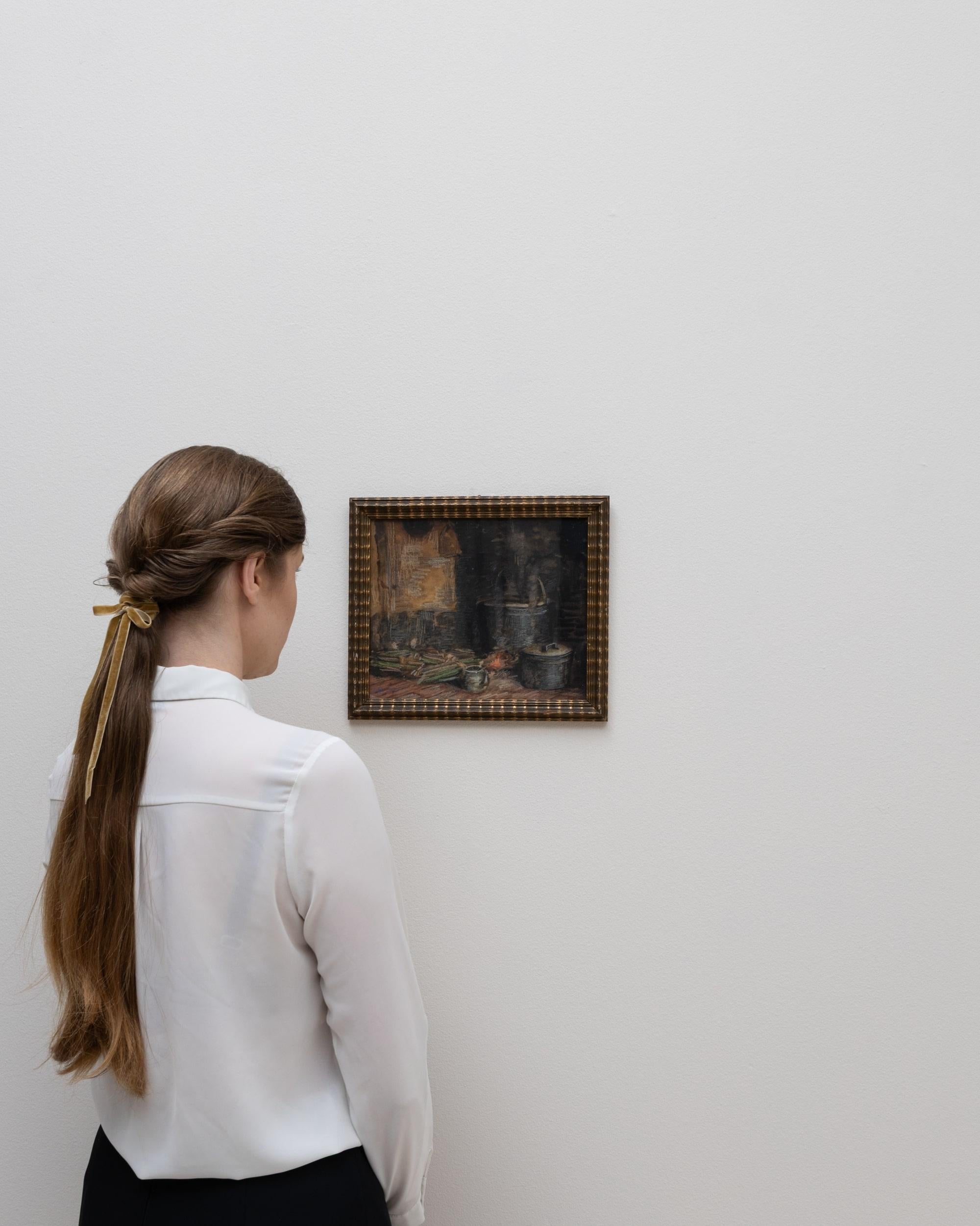 Este bodegón belga del siglo XX presenta una composición sombría y atmosférica centrada en humildes objetos de cocina dispuestos sobre un fondo oscuro y texturado. Ollas, sartenes y vasijas se sitúan junto a verduras y productos dispersos, sus