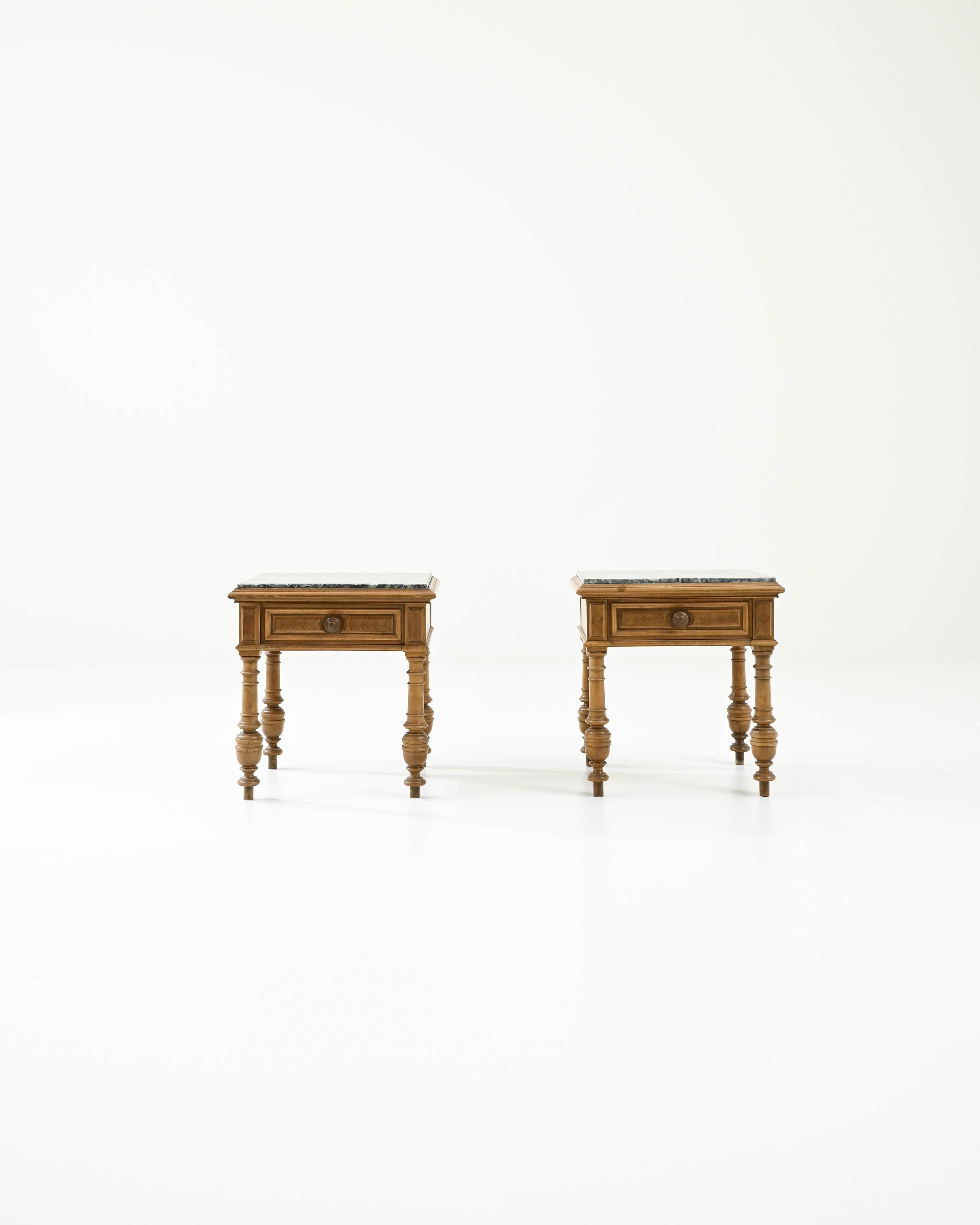 A pair of wooden side tables with marble tops created in 20th century Belgium. Ornate and expertly crafted, this smart pair of tables brings a dignity and calm to the space. The combination of masterfully lathed legs and dazzling green marble top