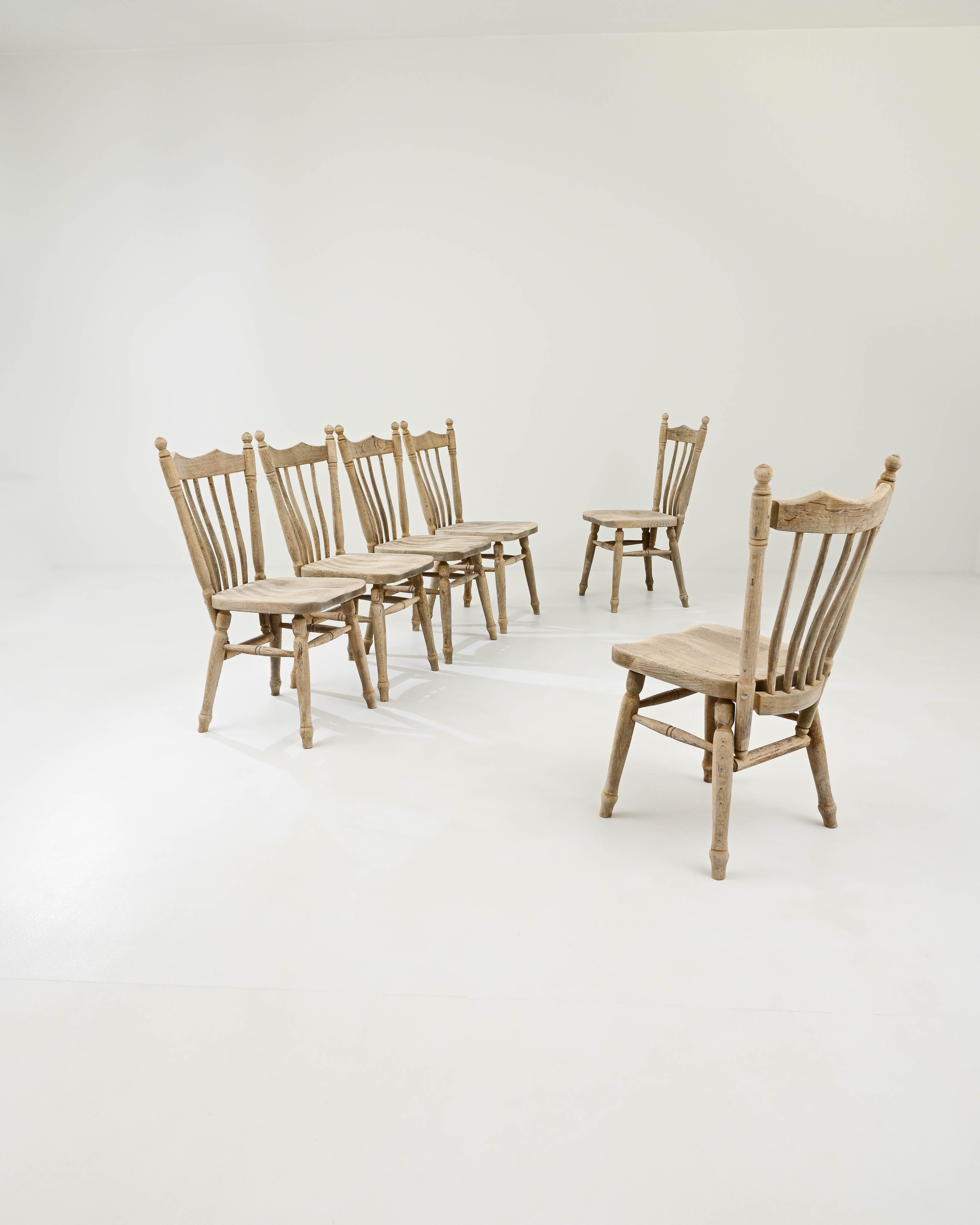 A set of wooden dining chairs created in 20th century Belgium. Created in a classic Belgian farmhouse style, these chairs exude a sense of dignity, while inviting one to sit with a palpable warmth. Gentle tapering back supports, thoughtfully lathed