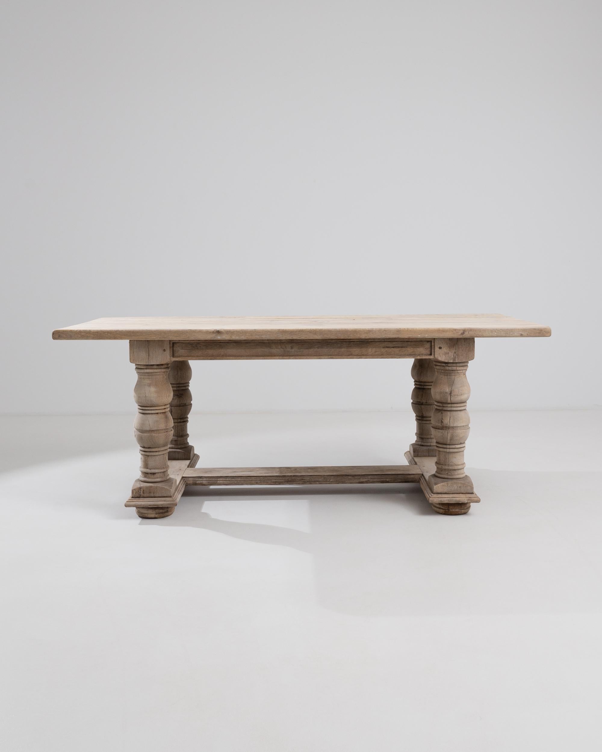 A 20th century belgian bleached oak dining table. This large trestle table is marked by regal craftsmanship: colossal legs are carved with precision, careful profiles completing the edges of each piece. Refreshed with a natural finish in our