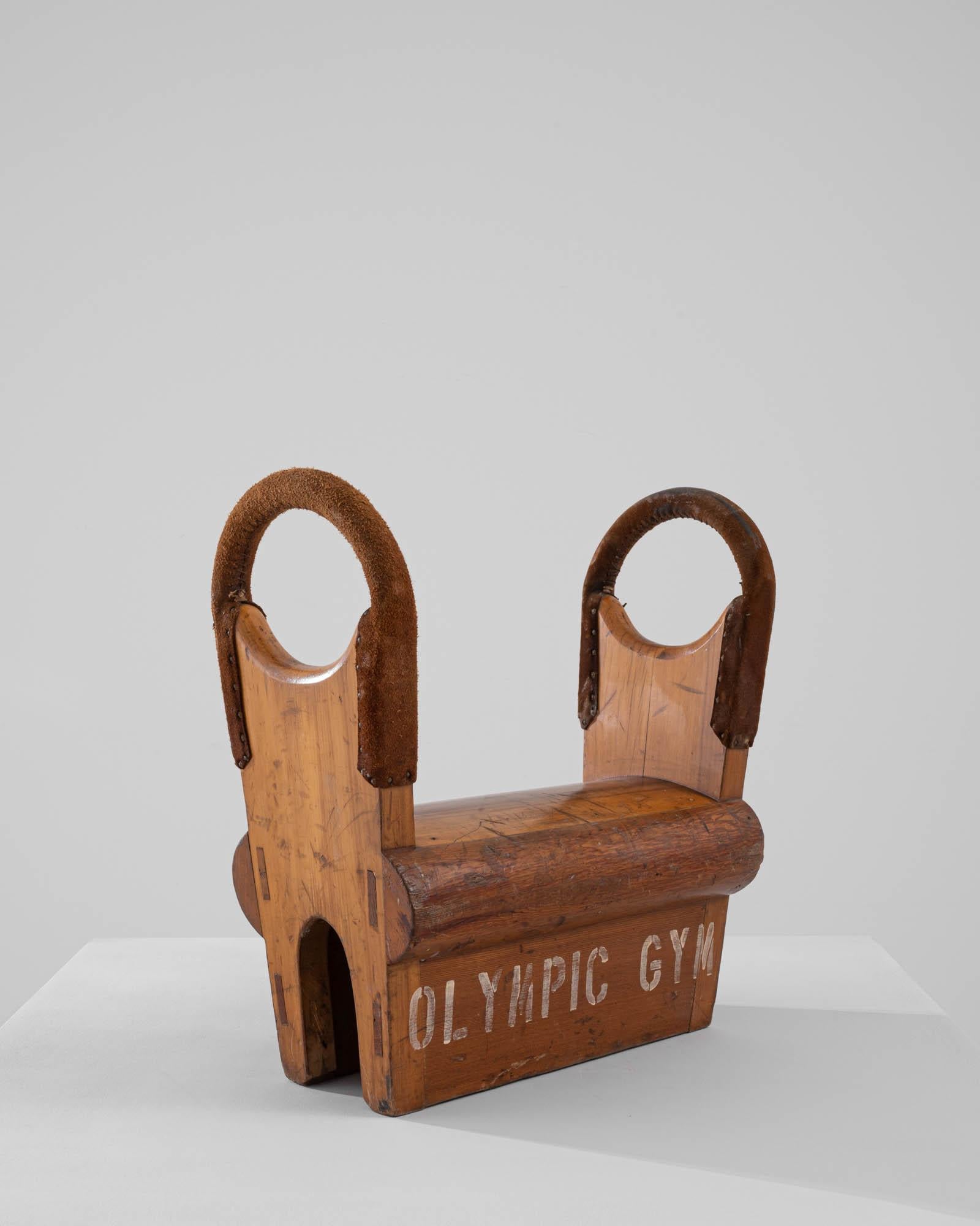 A wooden gymnastics apparatus created in 20th century Belgium. Originally created to assist in calisthenic exercises, this bench is well served by its heavy construction and sturdy base. Originally manufactured in Belgium, yet used at the Olympic