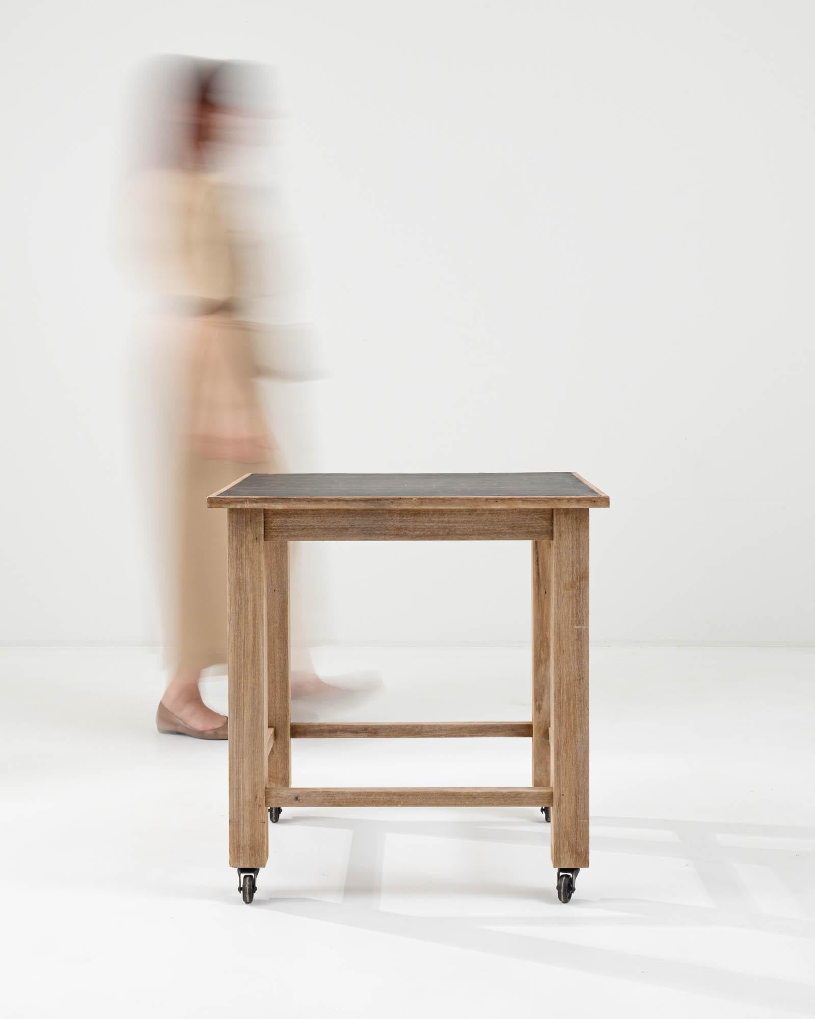 Elevate your space with the functional simplicity of this 20th Century Belgian Wooden Side Table on Wheels. Its light oak base provides a natural and inviting touch, while the dark black wooden top offers a striking contrast. The small, dark wheels