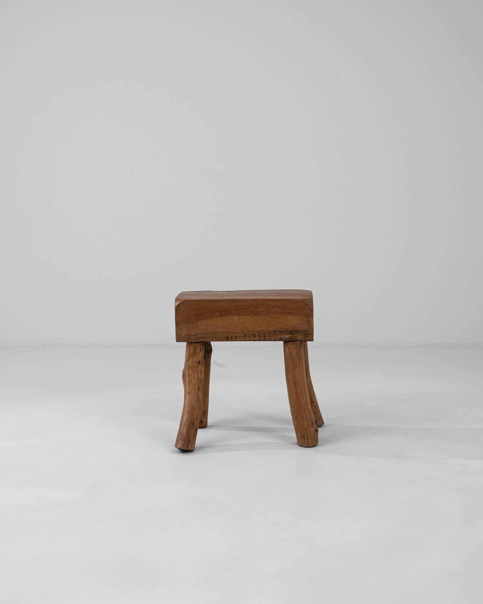 This 20th Century Belgian Wooden Stool exudes a robust and earthy charm, making it a timeless addition to any interior. Crafted from solid wood, the stool showcases natural grain patterns and knots that tell the story of its rustic origins. The