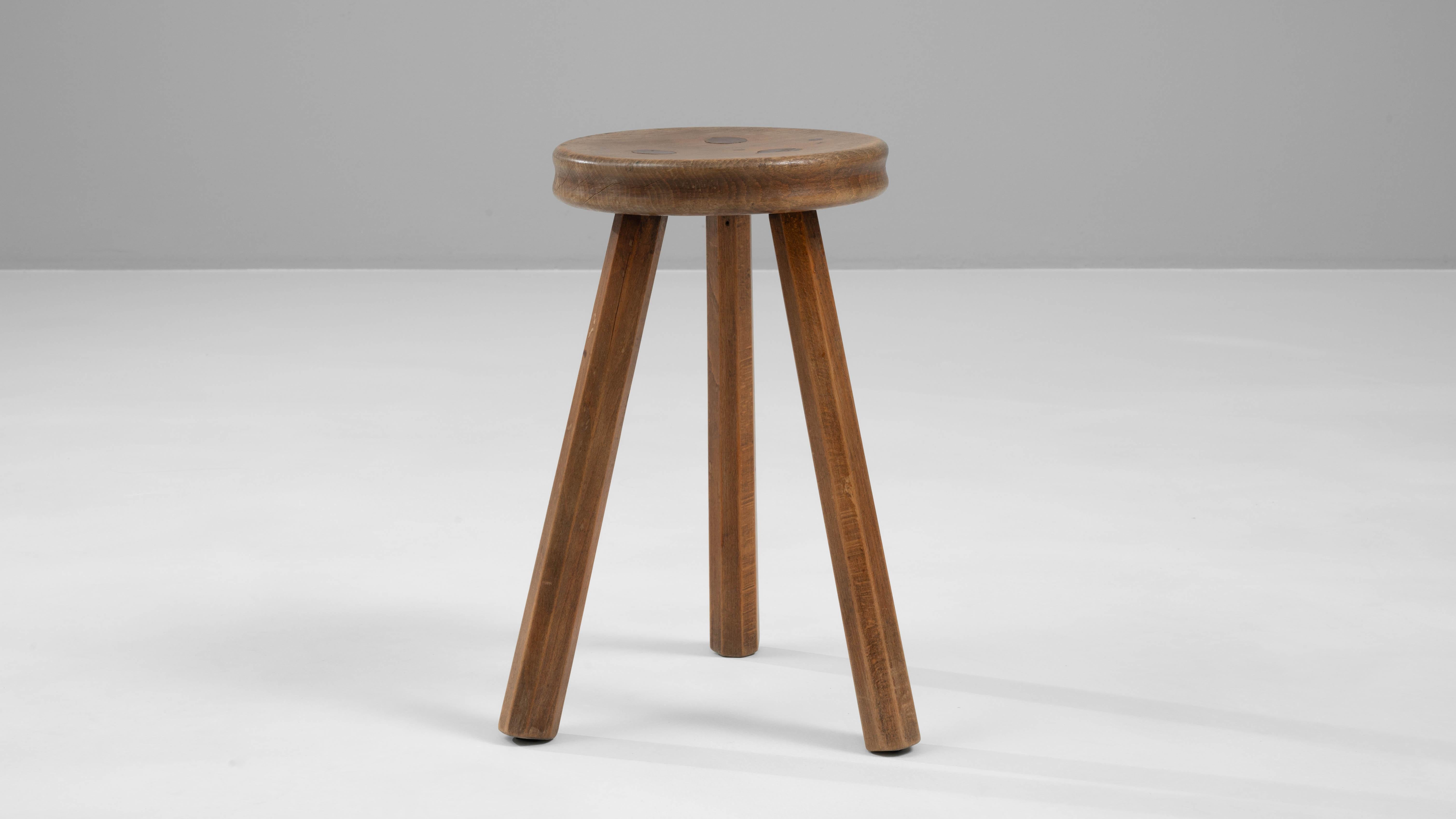 Apportez une simplicité classique et un style durable à votre intérieur avec ce tabouret en bois belge du 20e siècle. Fabriqué de manière experte à partir de bois de haute qualité, ce tabouret met en valeur les magnifiques tons riches de son