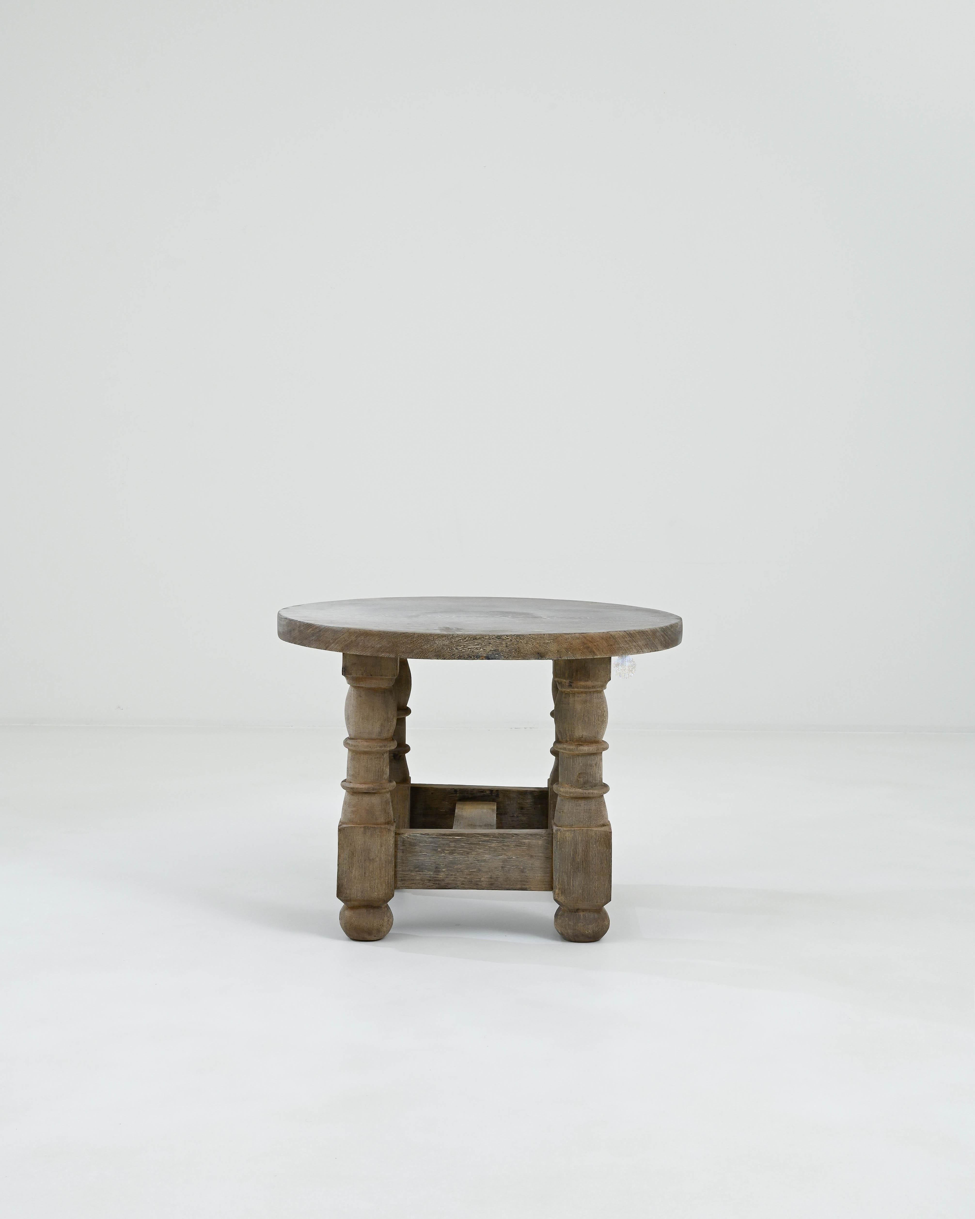 A wooden coffee table created in 20th century Belgium. Stout and sturdy, this dark brown circular coffee table boasts an elegance that charms the eye and brings the room together. Four thick legs, which have been artfully lathed, connect together in
