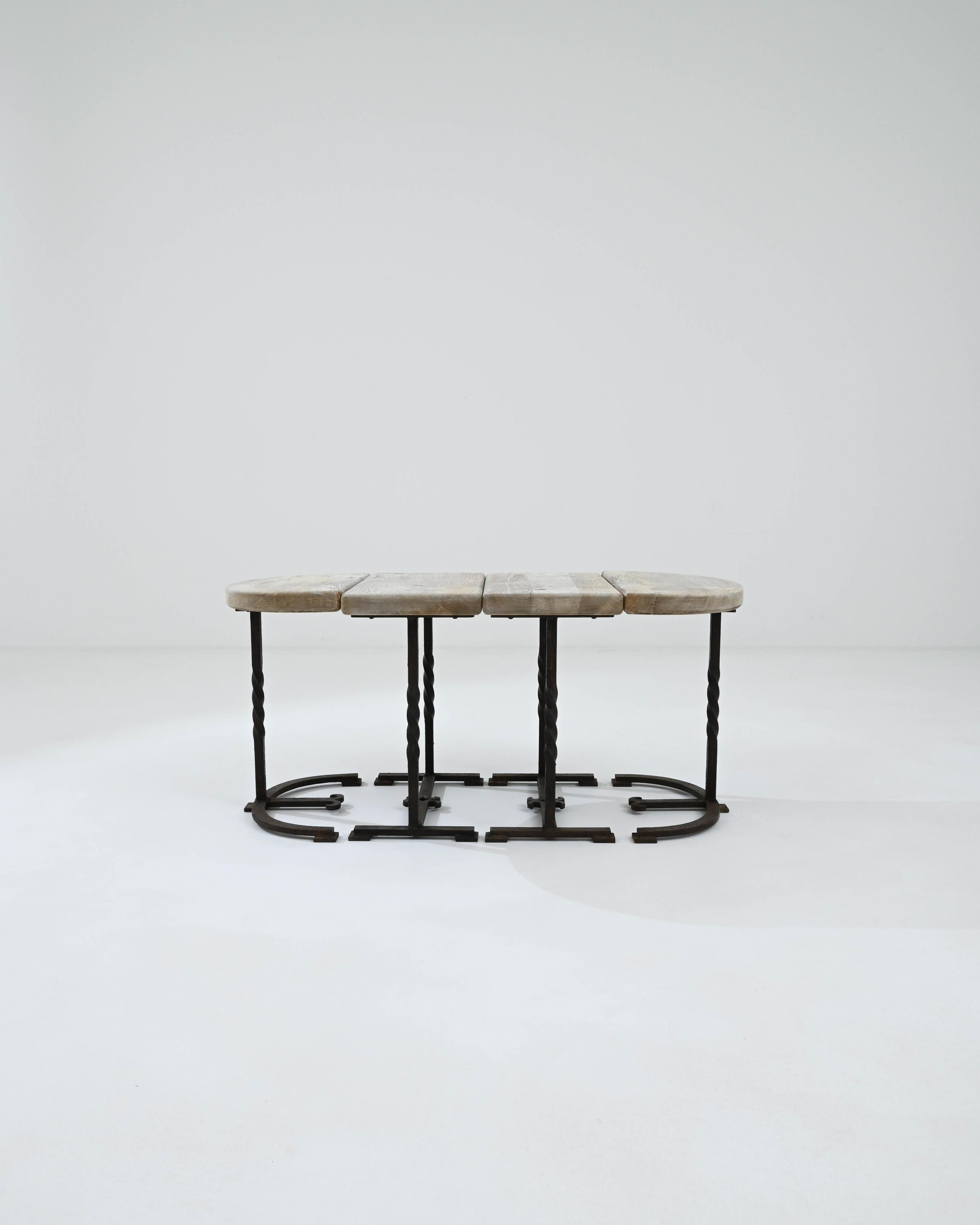A set of four metal and wooden tables created in 20th century Belgium. Modular, expertly composed, and created from thoughtful materials, this set of small tables charms the eye. Twisted wrought iron and thick slabs of lumber make up four individual