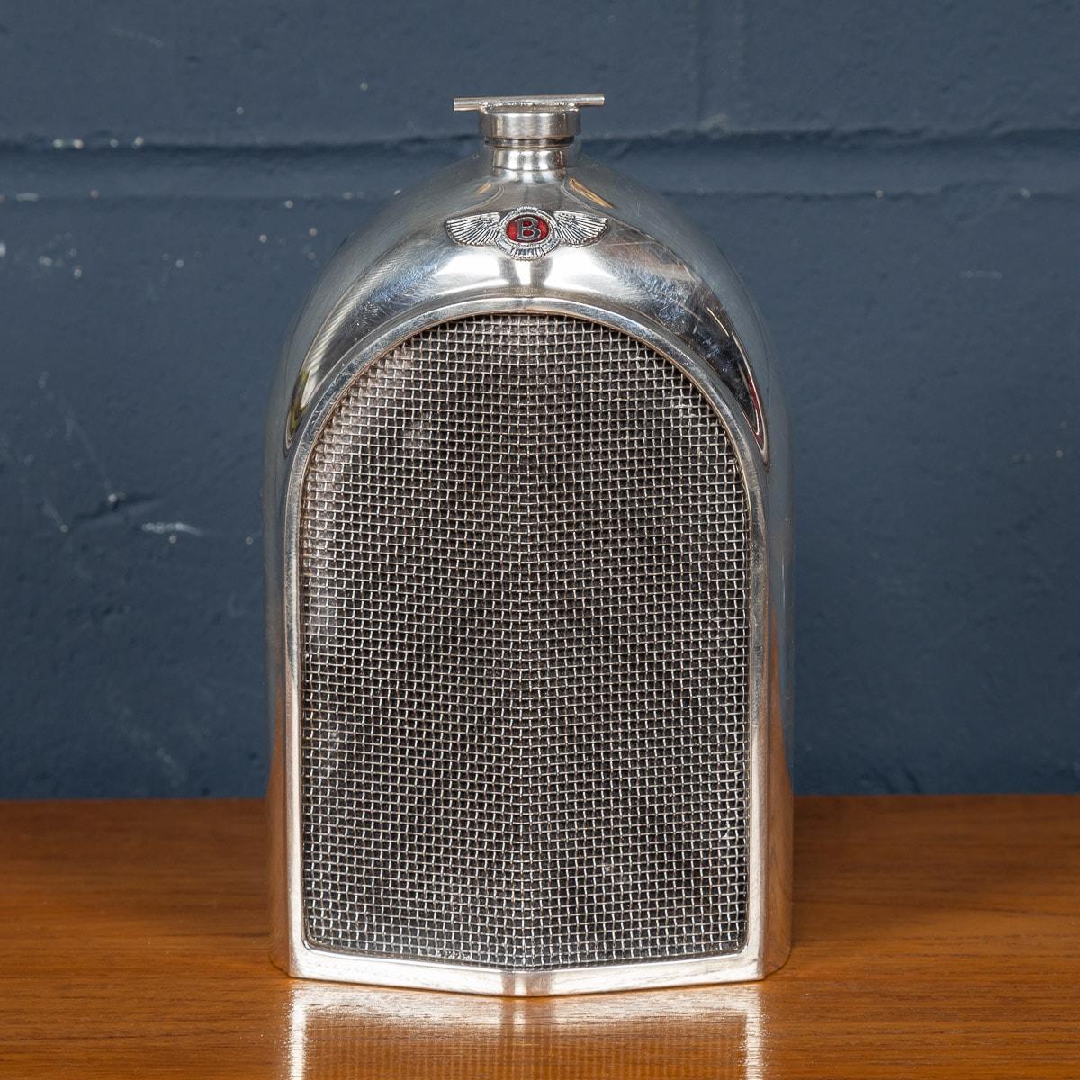 A vintage Bentley chrome radiator grille decanter made by Classic Stable Ltd of Worthing with wire mesh grille, bearing the red enamel radiator badge. Made in the 1970s, the decanter is equipped with a “slot” in the casing at the rear allowing
