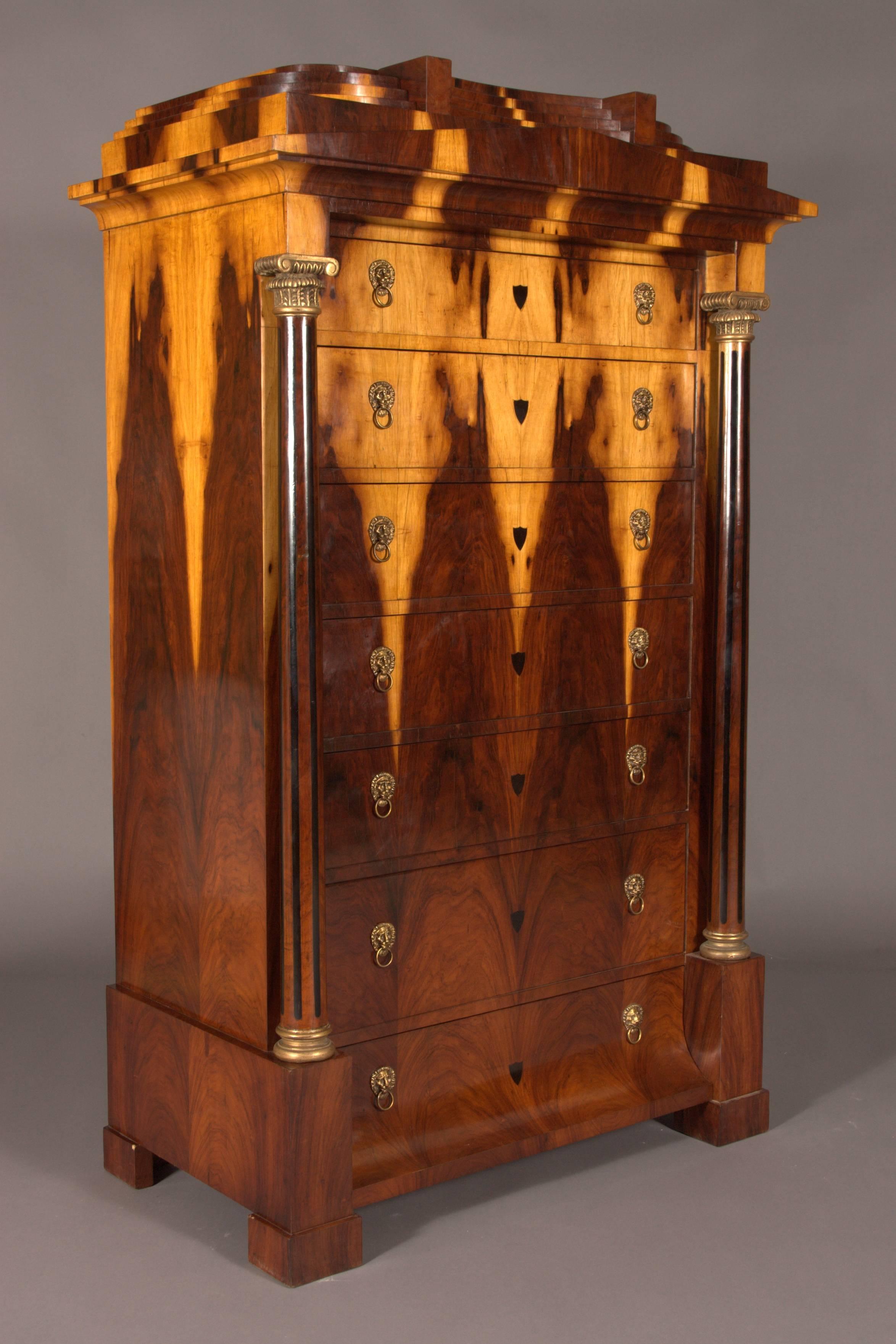 Exotic Indian Palisander on solid conifer. Architecturally arranged front. High-right body on padfoot feet. Provided with seven drawers of different sizes. The base drawer is curved. Surrounded by two full columns of massive beech, carved gilt bases