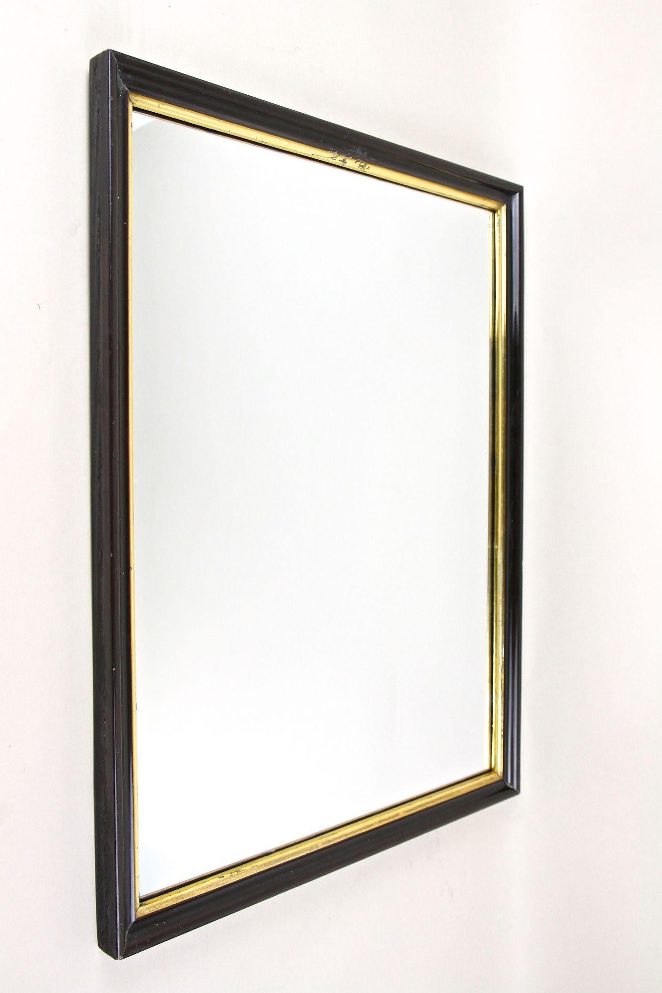 Miroir Art Déco du 20ème siècle au design intemporel, datant de l'époque en Autriche autour de 1920. L'élégant cadre laqué noir présente une belle surface brillante et impressionne par son design.  La barre intérieure dorée est également décorée, ce