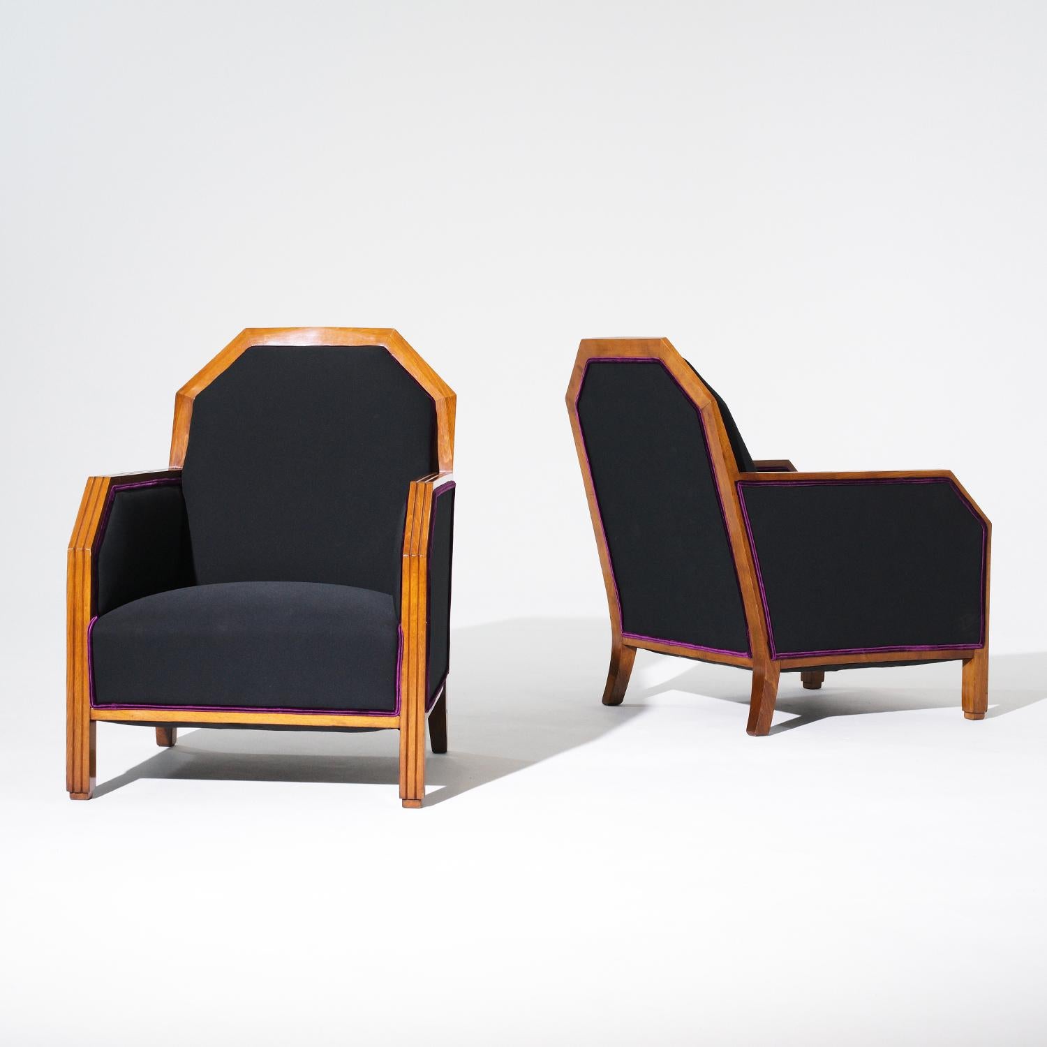 A vintage French Art Deco pair of club chairs made of hand crafted tinted Birchwood, in good condition. The detailed Parisian lounge chairs are upholstered in a black linen fabric. Minor stain on one of the chairs, due to age. Wear consistent with