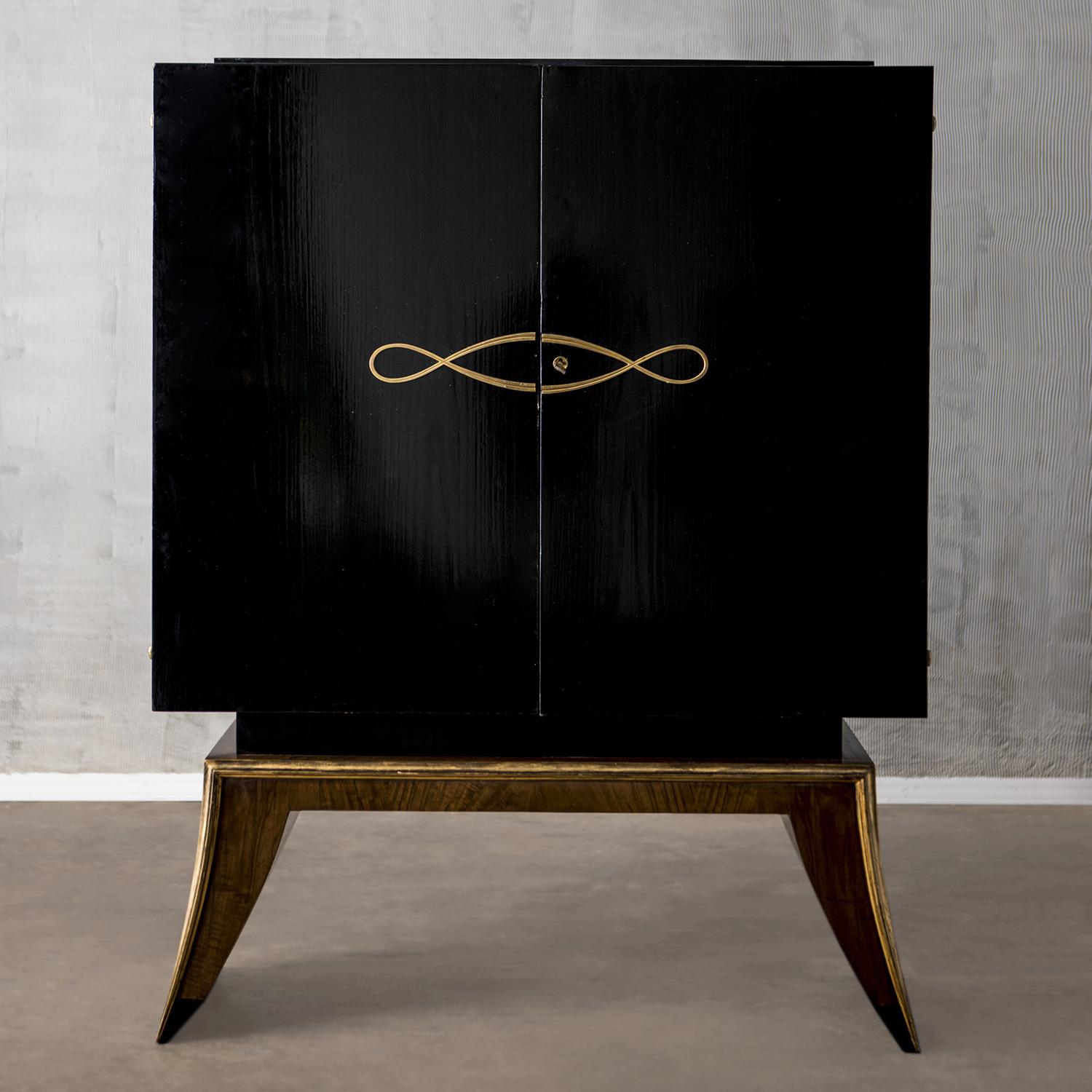 A vintage Art Deco French cabinet with a lustrous ebonized black finish, enhanced by detailed brass décor in good condition. The tall polished cupboard is composed with two doors, consisting two shelves and two drawers made of hand crafted mahogany