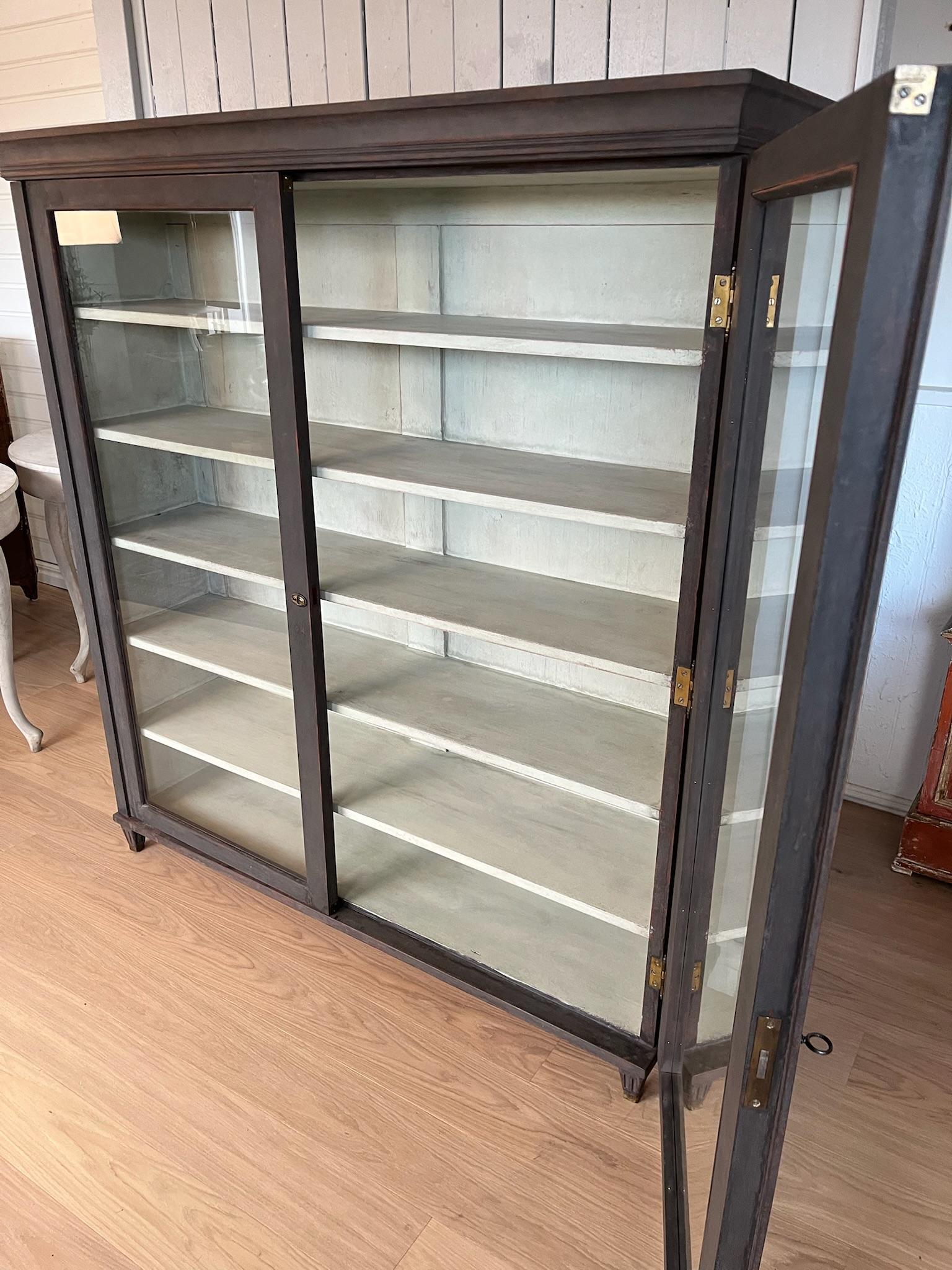 Una magnífica Librería Expositora con dos puertas de armario acristaladas

Pintado y repintado en negro con un delicado toque de rojo bajo y angustiado para dar una auténtica sensación de antigüedad
El interior también está pintado de verde claro,