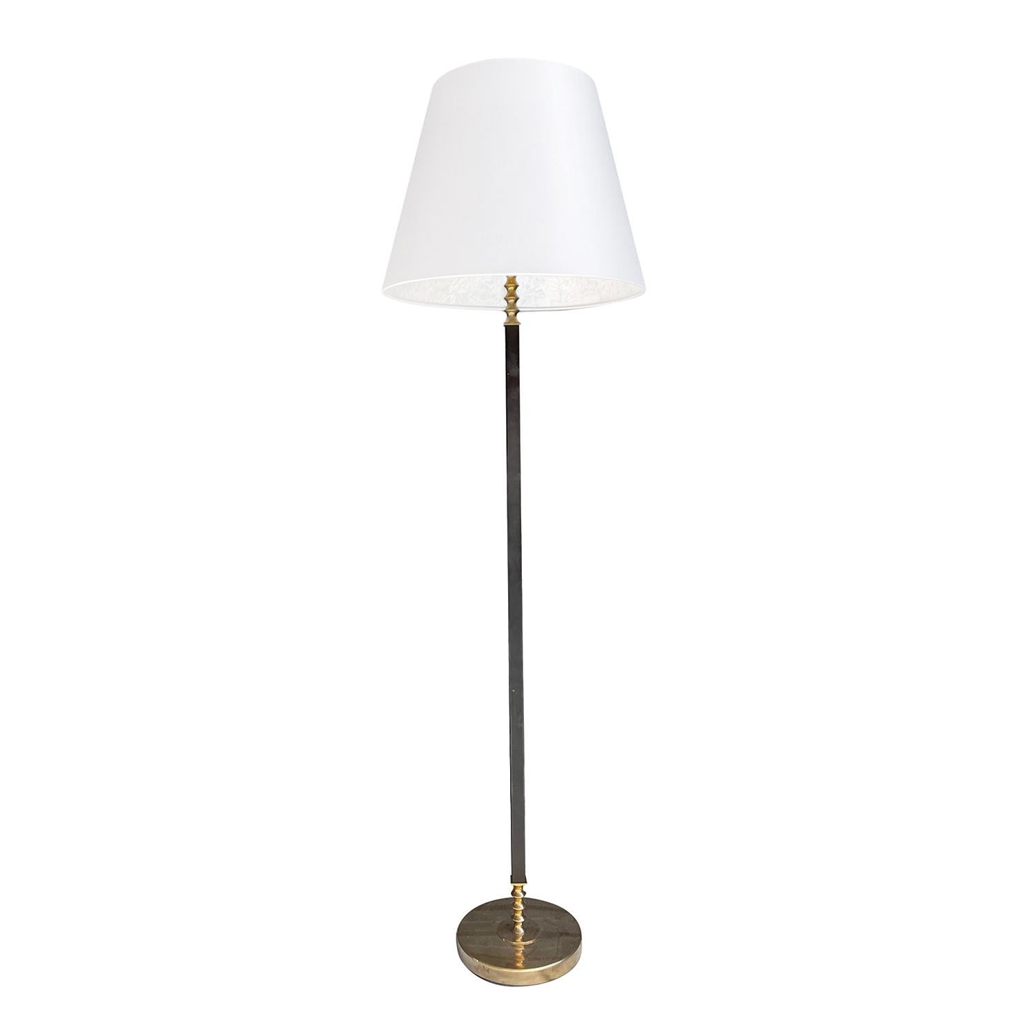 A black, vintage Mid-Century Modern Swedish floor lamp with a new white round shade made of hand crafted lacquered metal, produced by Böhlmarks in good condition. The steam of the Scandinavian light is enhanced by detailed brass rings, featuring a