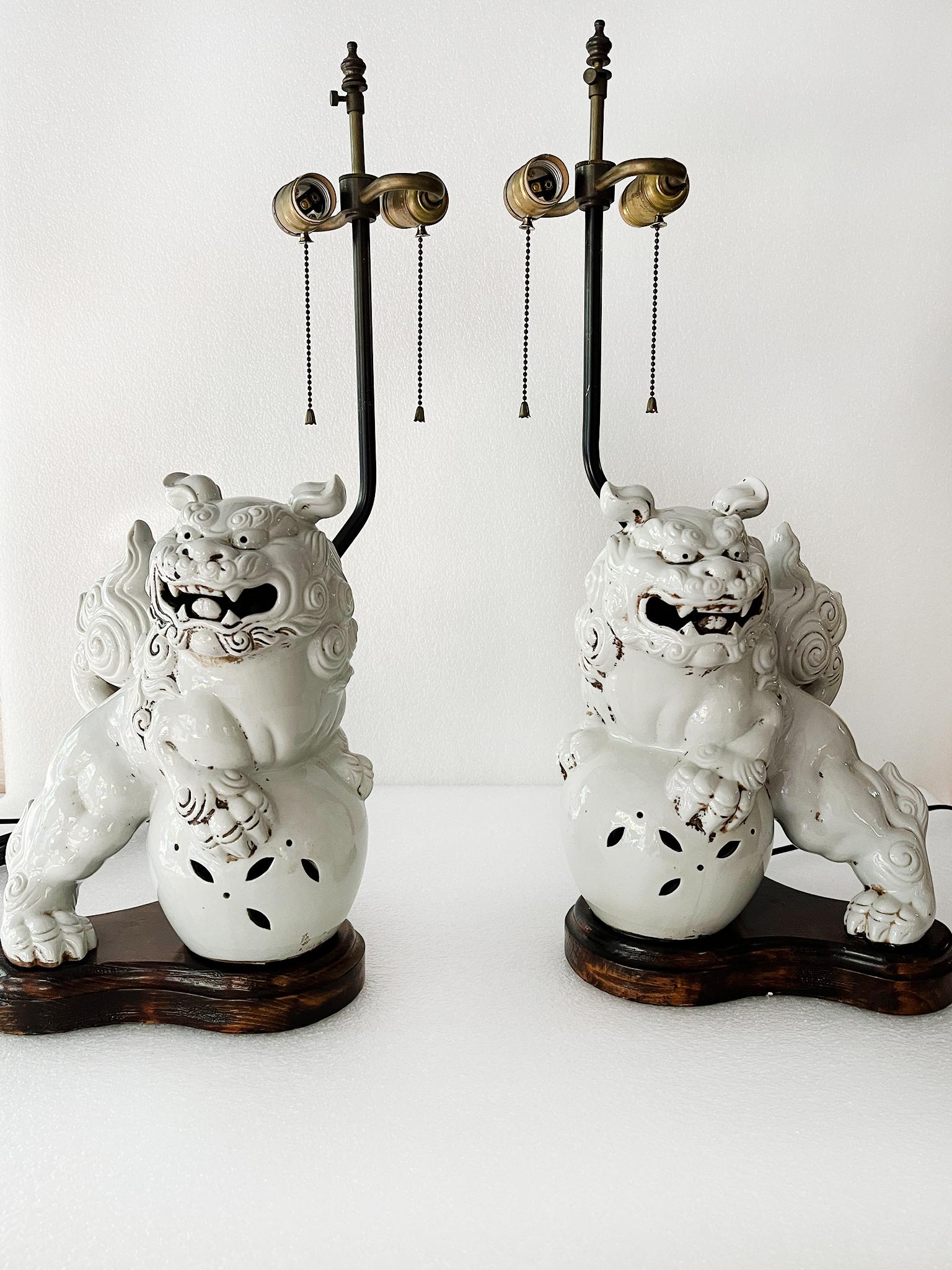 Fabriquées au 20e siècle, ces charmantes lampes de table en forme de chien de foo sont constituées de corps en blanc de chine sur des bases en bois. Ils ont été récemment recâblés et sont équipés de douilles à double ampoule avec filetage