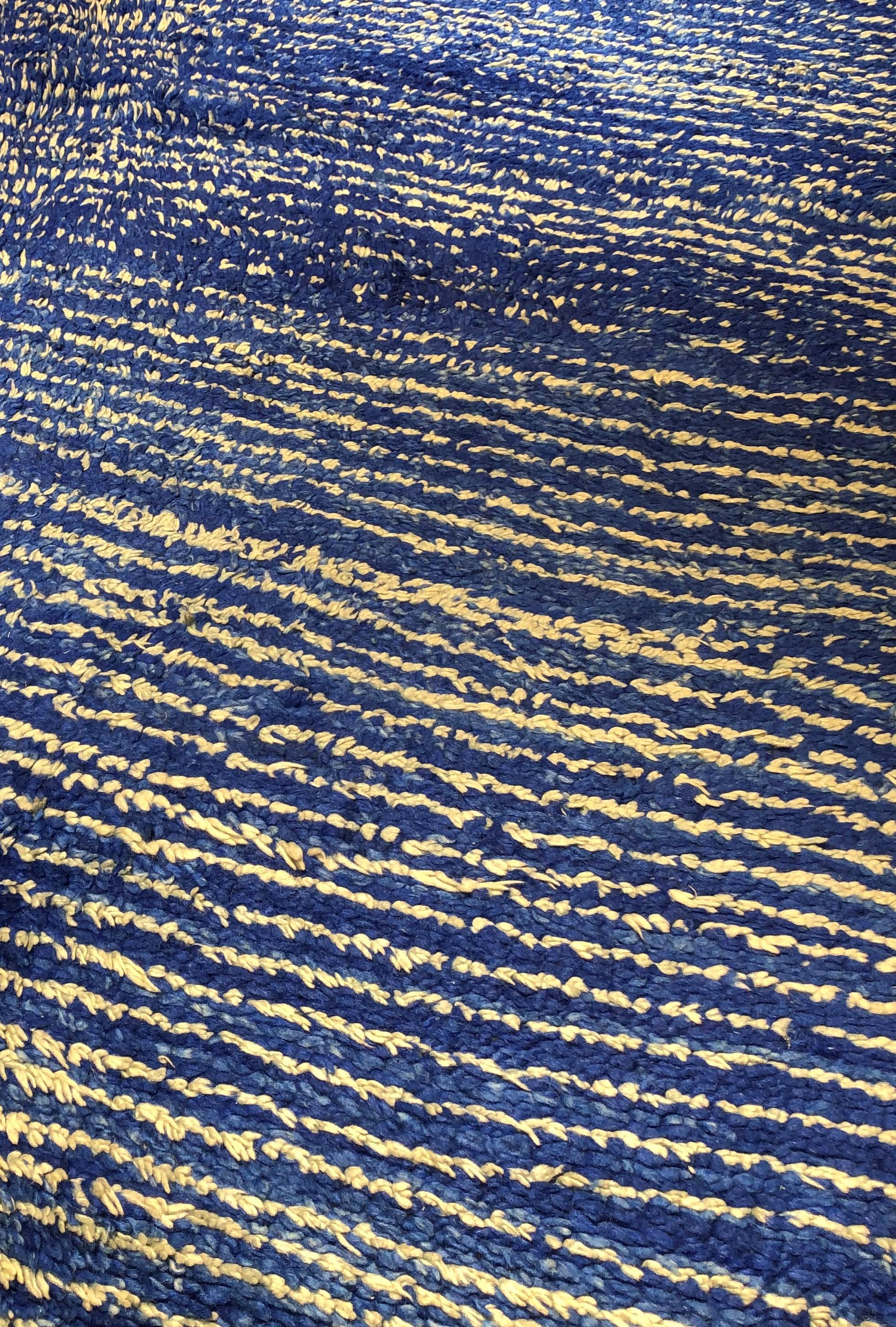 Berber carpet, Morocco, particularly rare for its graphic composition and colour. 
The thick wool is shiny and dyed with a cobalt blue mixes with shades of natural white wool to form irregular lines like waves that slide into the sea.