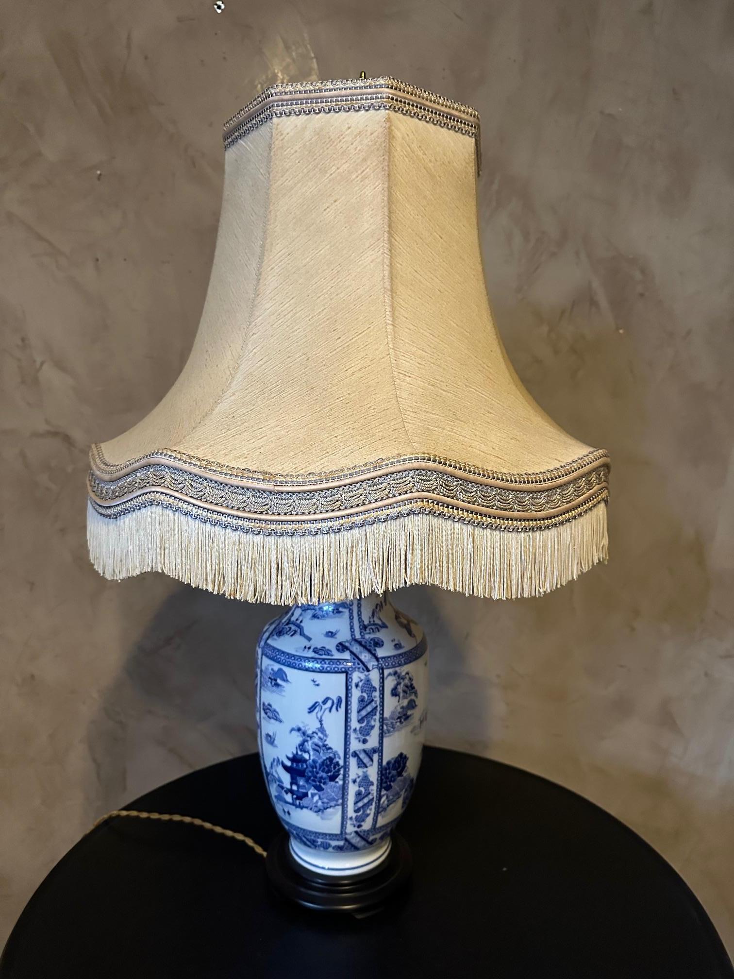 Large Chinese lamp in blue and white porcelain from the 1950s decorated with pagodas and characters.
Lampshade decorated with fringed trimmings in very good condition.
Wooden base. Brass tip. Very good overall condition. Original in its large size.