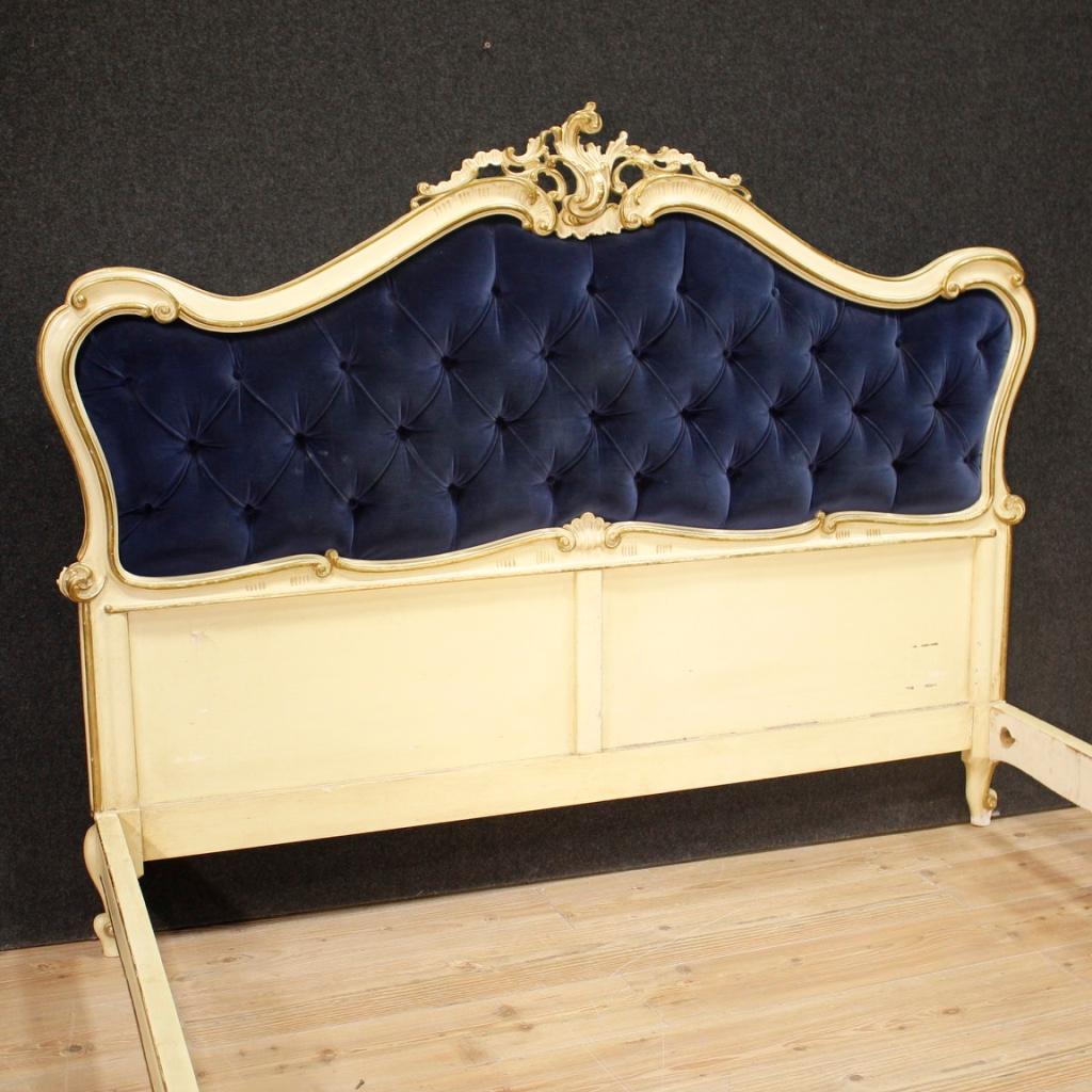 20th century Venetian bed. Furniture in carved, lacquered and painted wood with beautifully decorated floral decorations. Bed adorned with a headboard with blue capitonné velvet in good condition. Furniture that can accommodate an internal structure
