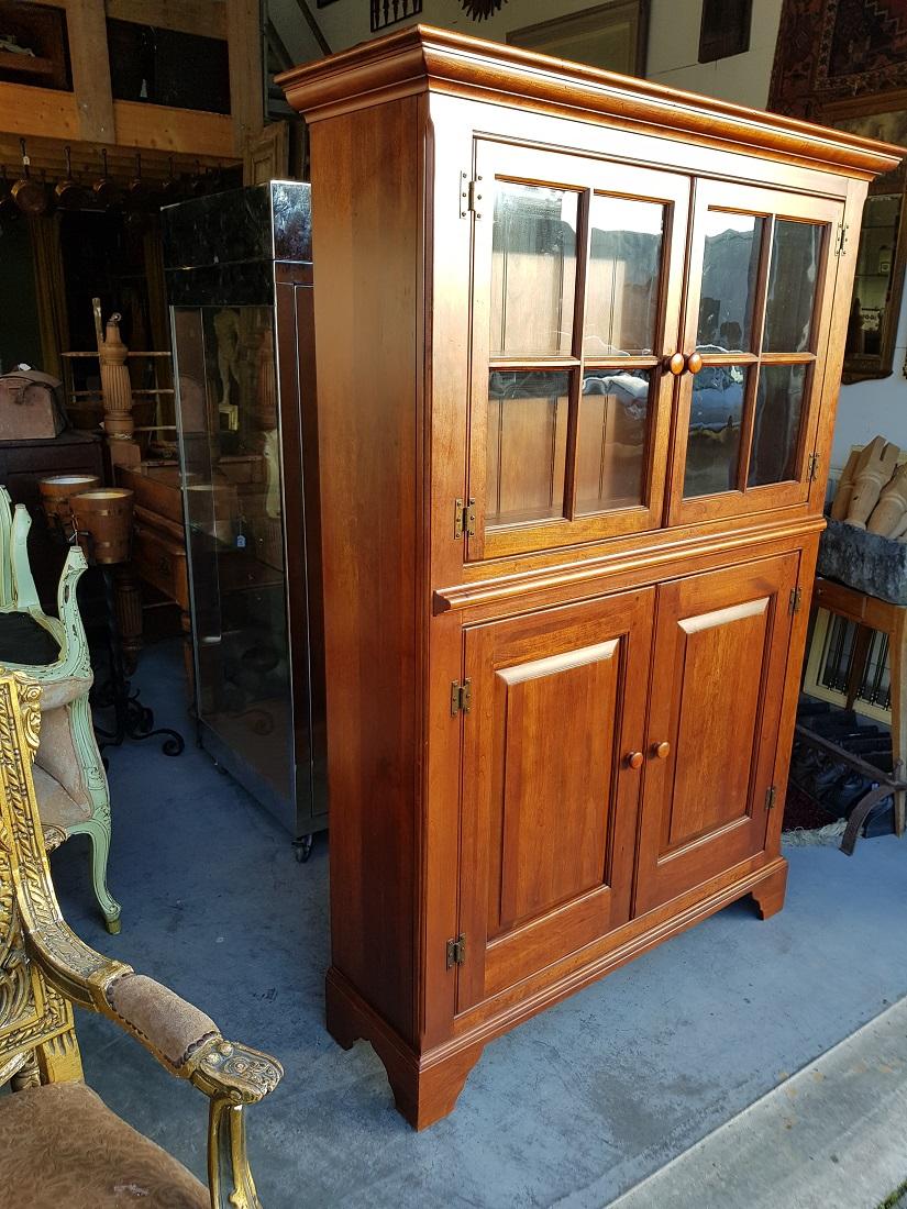 American cherry wood kitchen cabinet made by Bob Timberlake Lexington numbered 833-864 Kitchen Cupboard Made in USA, in the upper part 2 doors with glass panes behind which 1 shelf with slotted plates and at the bottom 2 doors behind which space for
