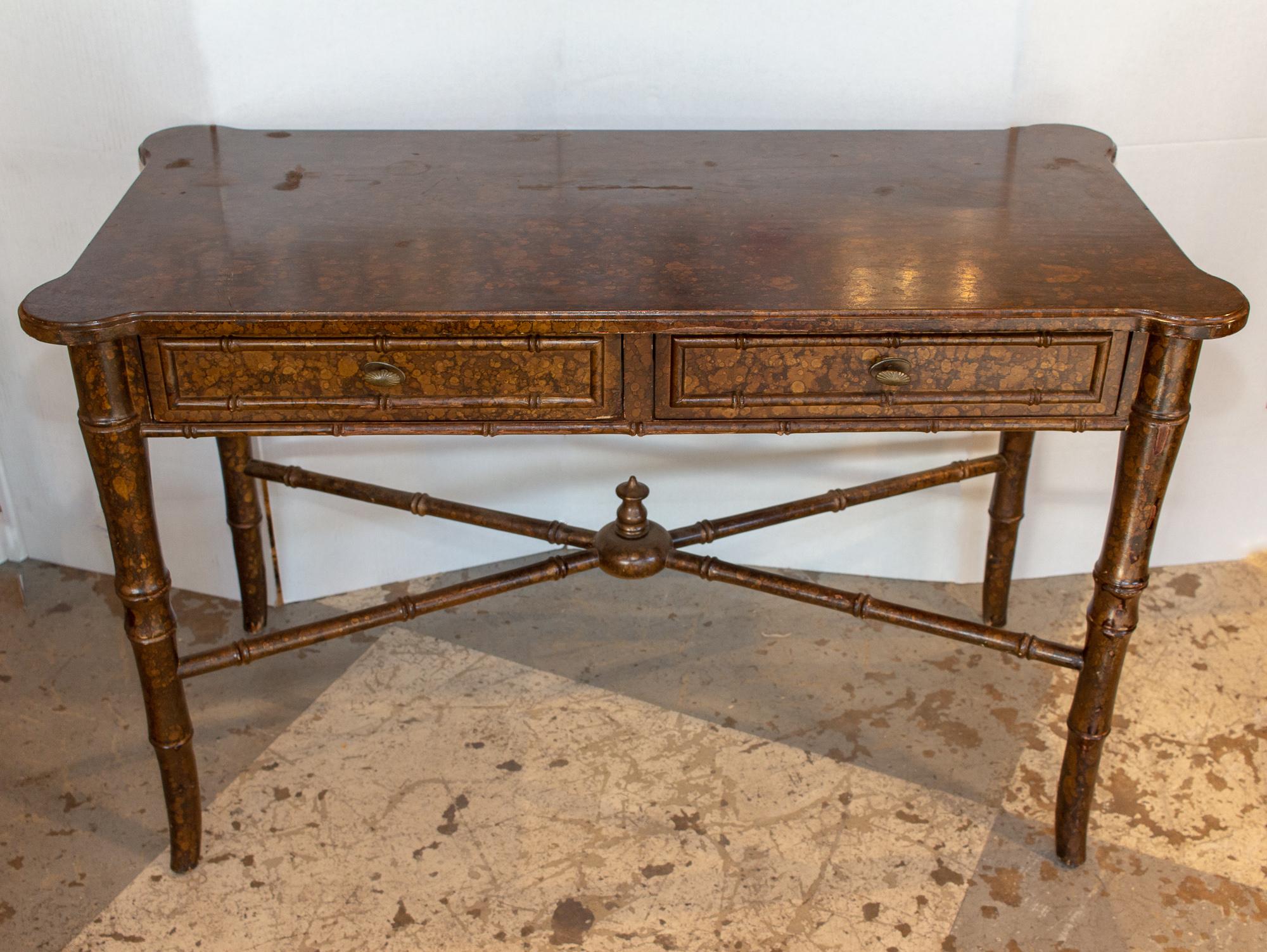 A lovely addition to the home, this vintage wood desk features a stylish bamboo detail and is painted with a lovely turtled / tortoise finish. Includes two pullout / pull-out drawers and a burnished brass pull. Signs of wear are seen on this piece