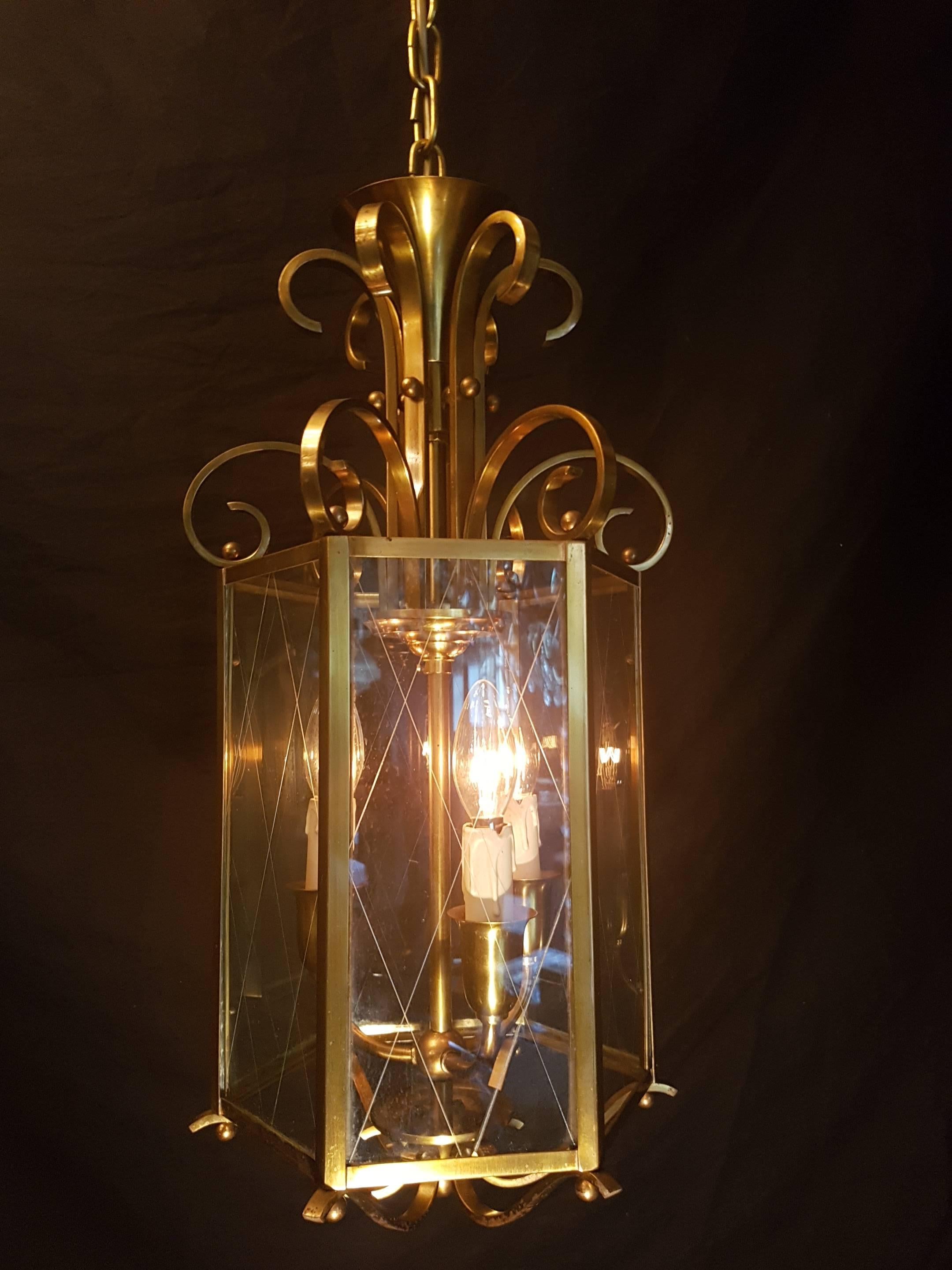 Three-light brass and glass hexagonal lantern with a delicate rhombic pattern on the glass.