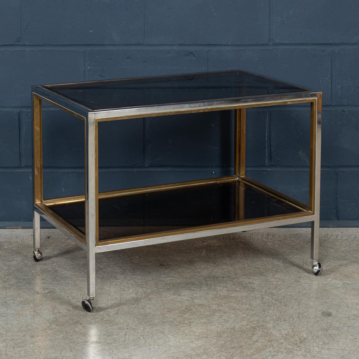 Un carrello portabevande elegante e sofisticato, progettato e prodotto da Belgo Chrome, caratterizzato da una straordinaria struttura bicolore in ottone lucido e cromo. Le linee architettoniche pulite del telaio forniscono una struttura robusta ma