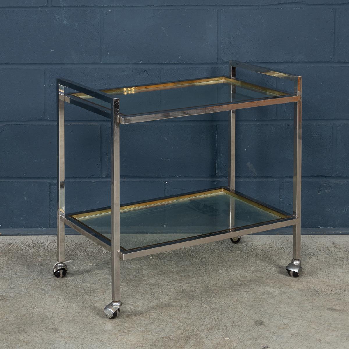 Un carrello portabevande elegante e sofisticato, progettato e prodotto da Belgo Chrome, caratterizzato da una straordinaria struttura bicolore in ottone lucido e cromo. Le linee architettoniche pulite del telaio forniscono una struttura robusta ma