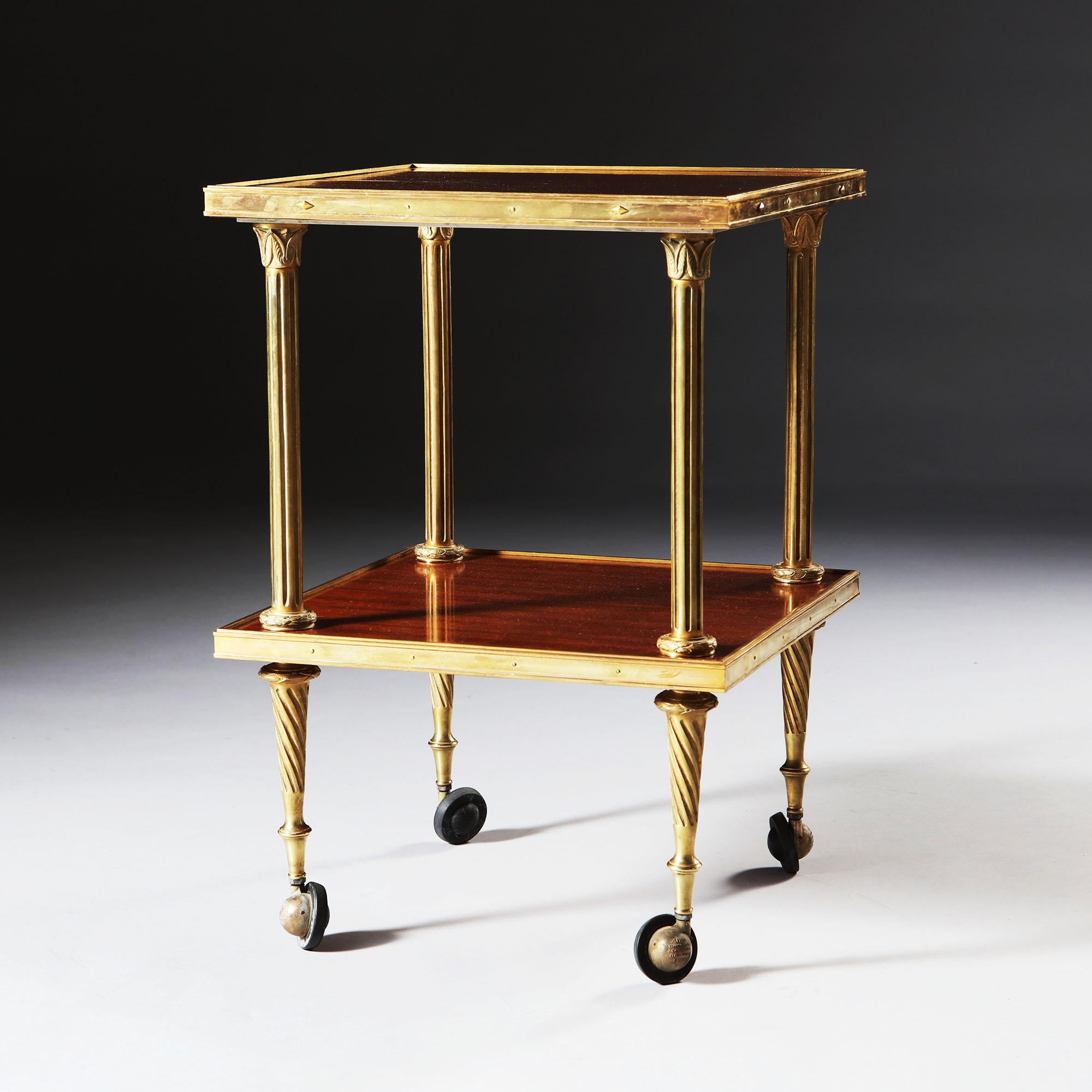 A fine brass and mahogany two-tier étagère by Maison Jansen, with pins and brass diamonds to the brass edges, fluted Corinthian column uprights and brass and rubber castors. Stamped JANSEN to the base.