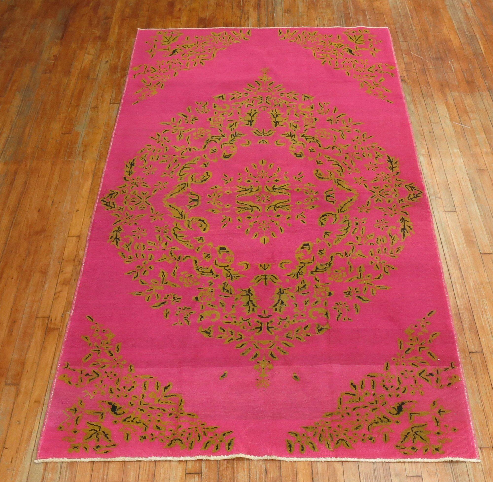 A late 20th century vintage one of a kind Turkish rug with a floral oval cornet motif in green and dark brown on a fuchsia ground.

Measures: 5'6'' x 10'2''.