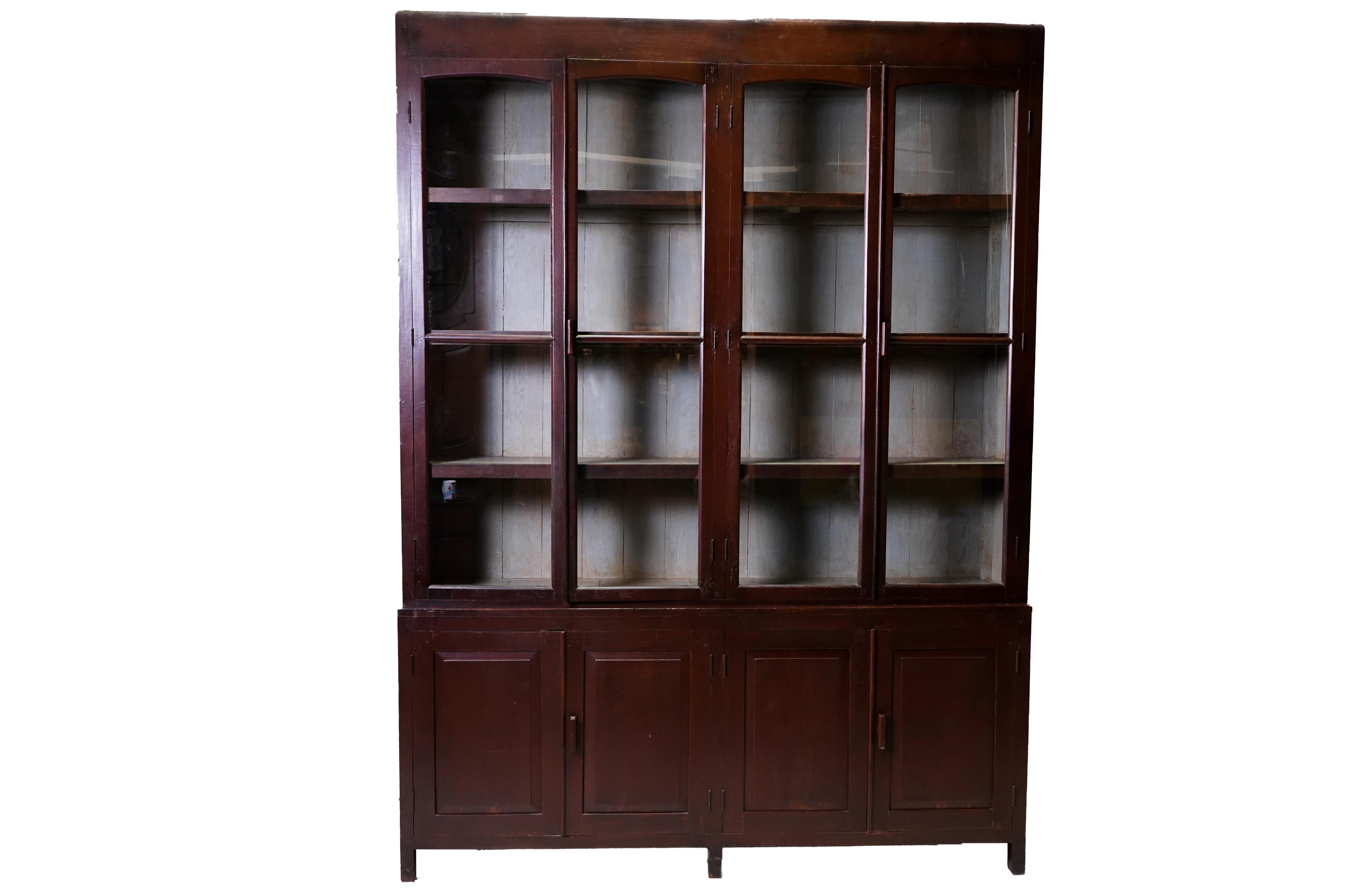 This impressively-scaled book cabinet was made from solid Teak wood and dates to the 1940's. During the late British empire in India and Burma much furniture was made in the Art Deco Style using local hardwoods and native furniture builders. Art
