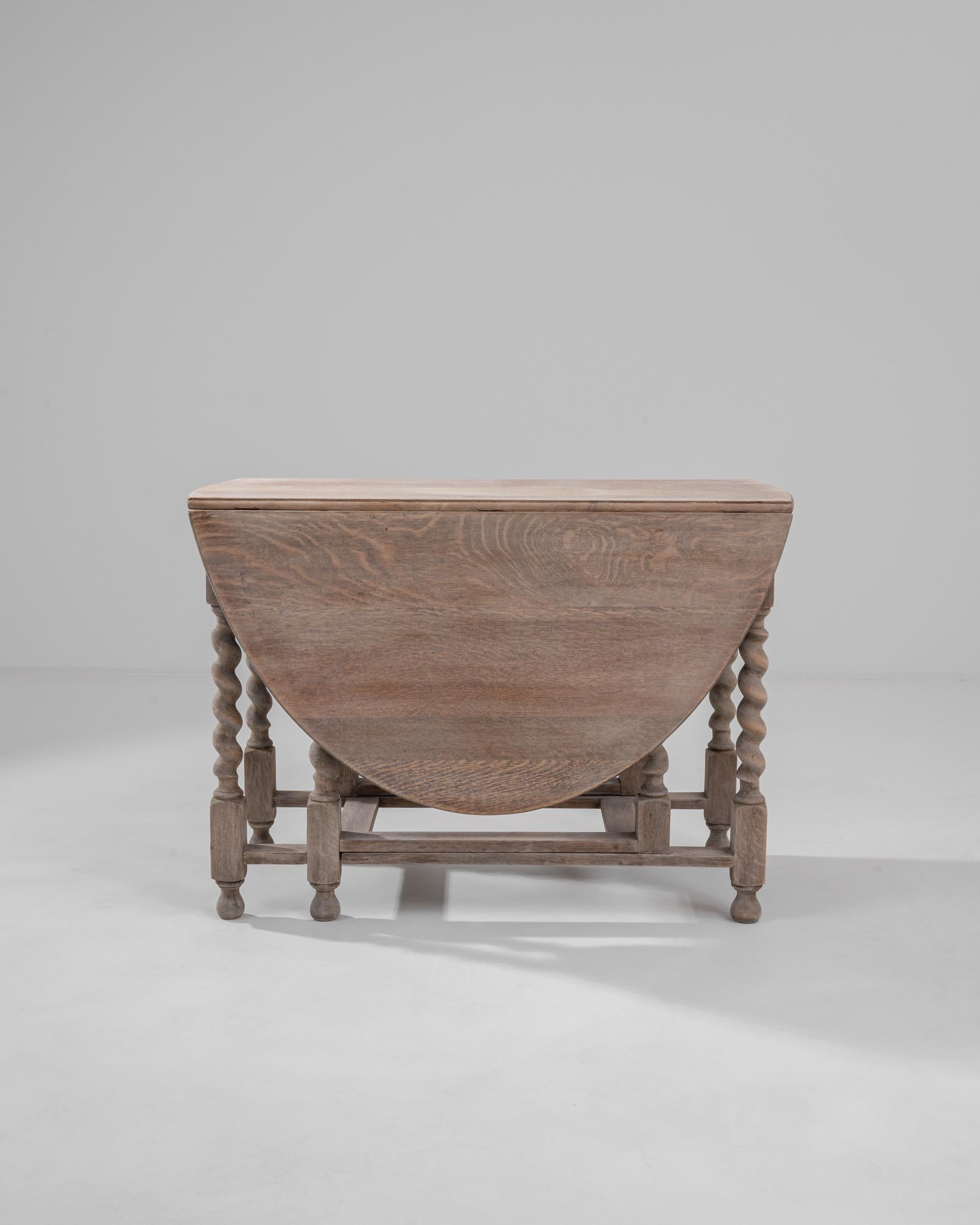 Graceful and versatile, this gate-legged table offers a covetable vintage find. Made in Great Britain in the 20th century, the design takes inspiration from the William and Mary style furniture of the 1600s. Barley twist legs atop teardrop feet