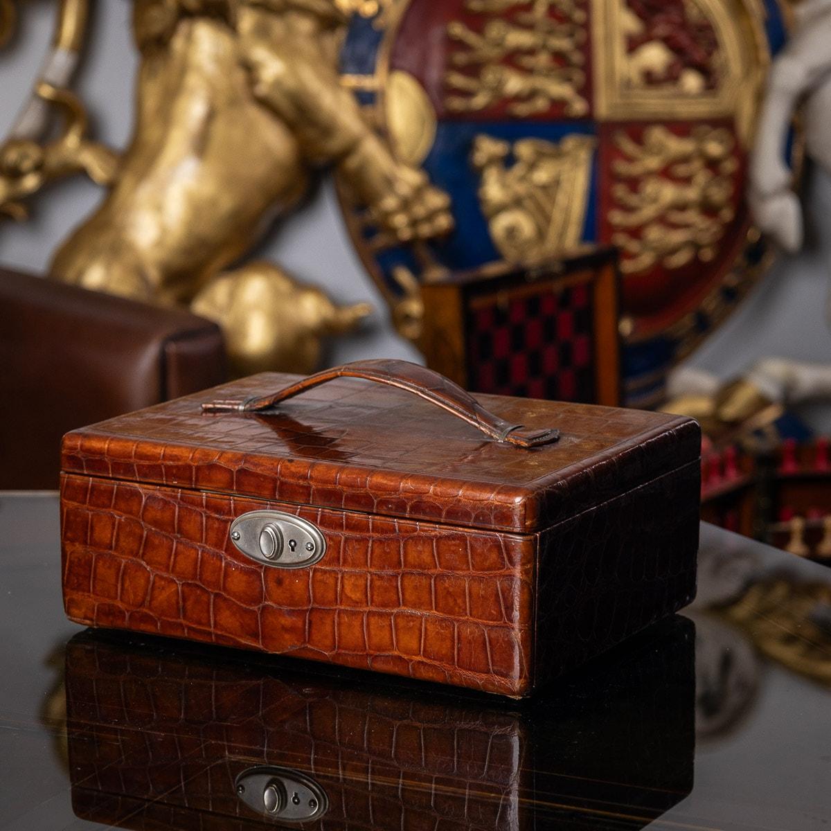 Antike Krokodilleder-Reisetasche aus dem 20. Jahrhundert. Der Koffer verfügt über einen Leder-Trageriemen am Deckel und einen Verschlussmechanismus an der Vorderseite. Das Innere ist mit weichem Wildleder ausgekleidet und hat ein herausnehmbares