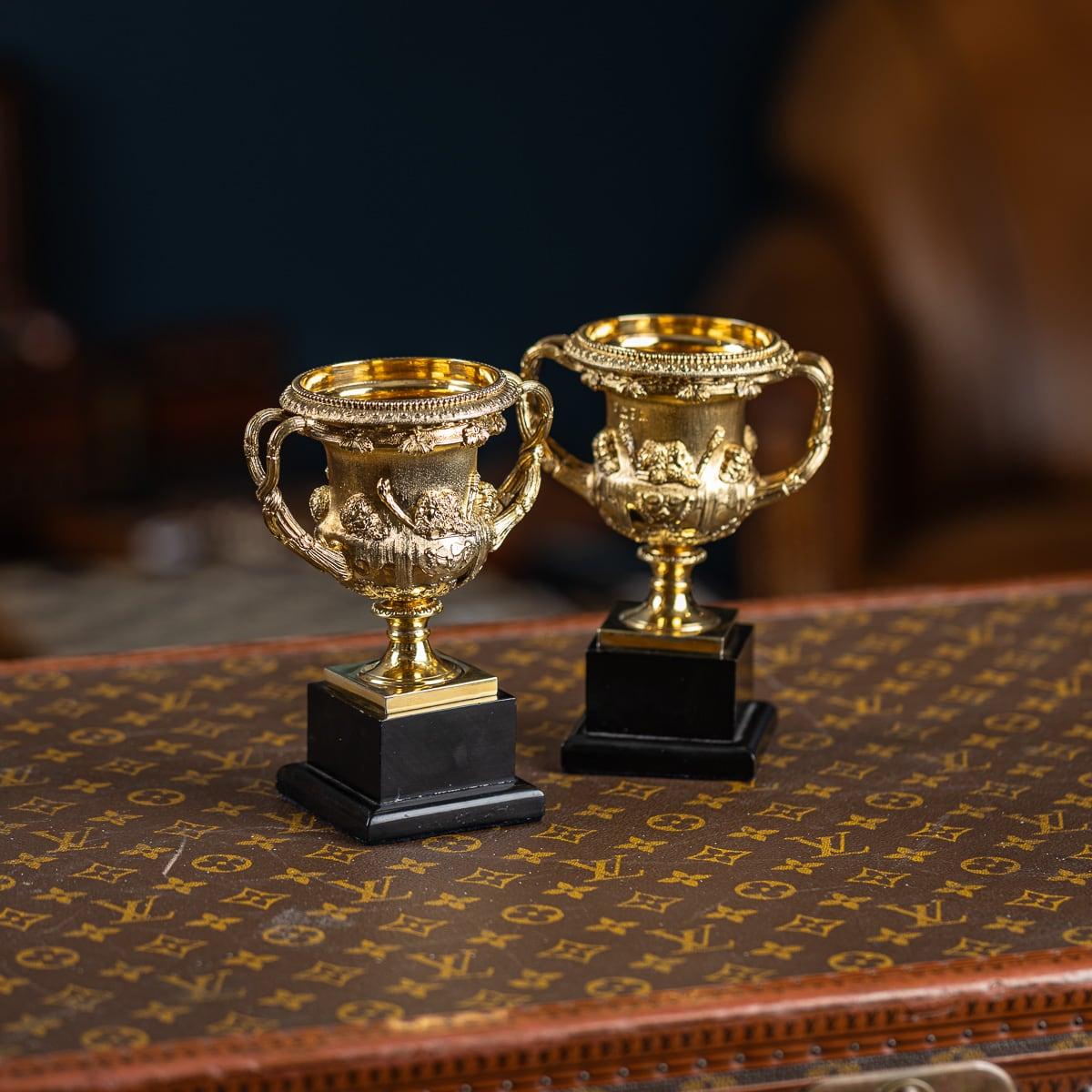Antica coppia di vasi Warwick in argento massiccio dorato dei primi del Novecento, eccezionalmente rara. Di forma tipica con decorazione a foglie d'acanto su basi quadrate ebanizzate. I lati sono applicati con teste classiche e pelli di leone. I